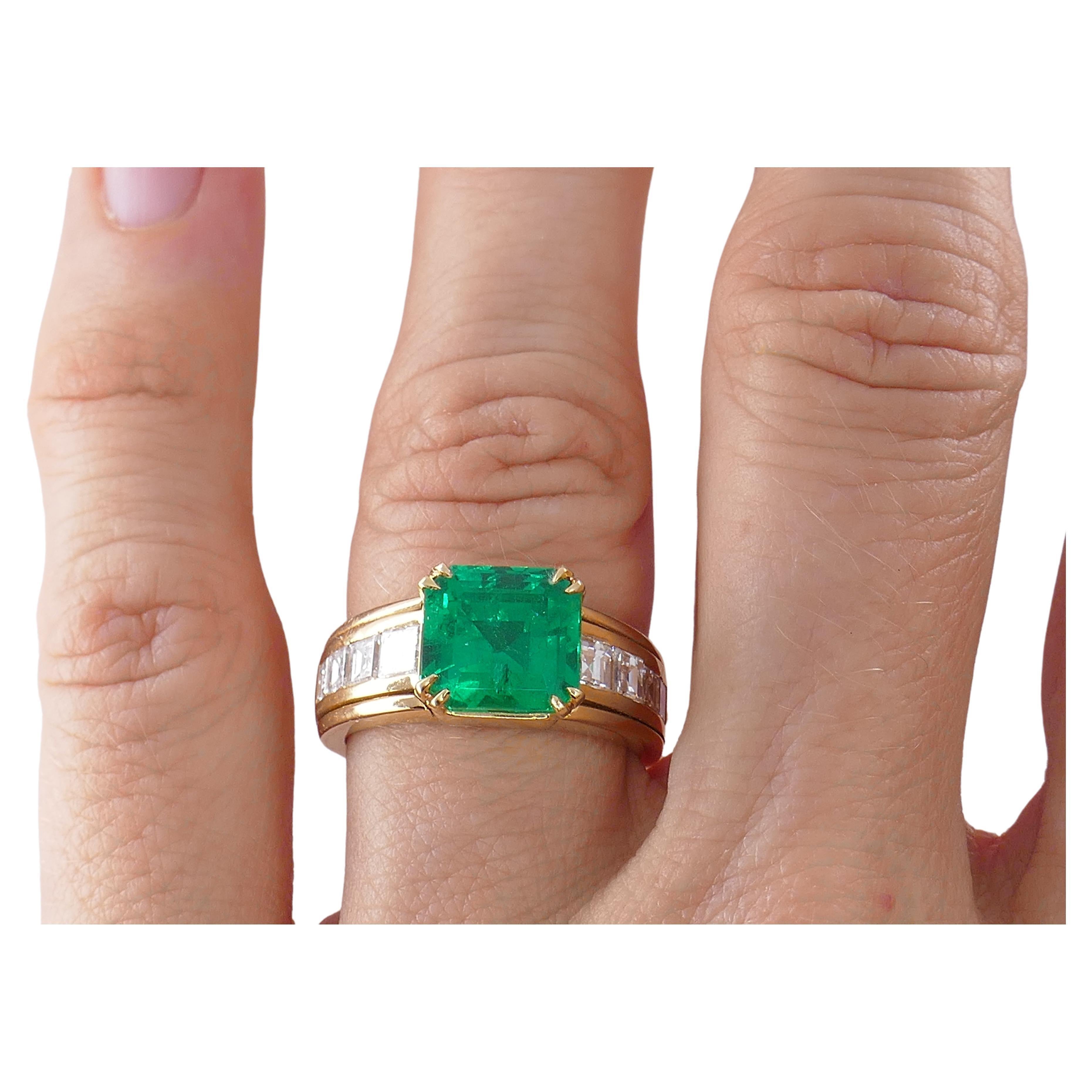 A gorgeous emerald ring, made of 18k gold, featuring diamonds.
It's a classic ring with an emerald cut emerald (supposedly Columbian), four prong set. Four emerald cut diamonds (eight in total) are channel set in the shank, on the sides of the