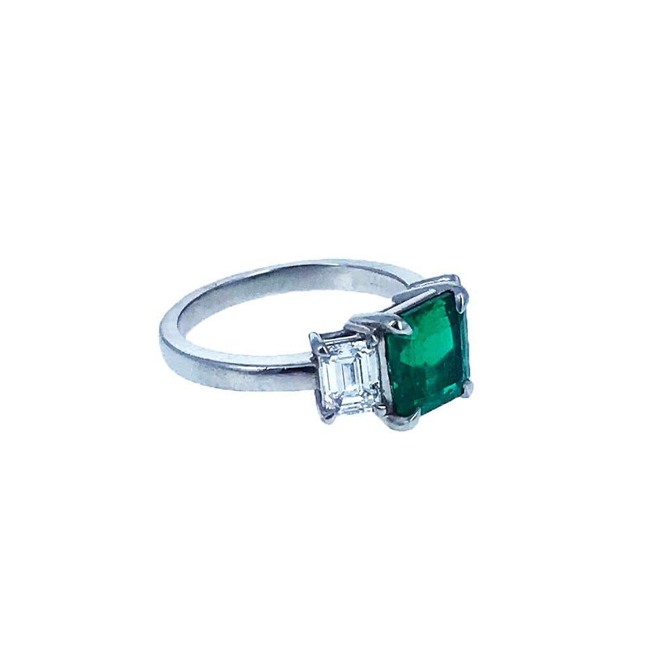 This lovely ring centers upon a square-cut emerald weighing 1.85 carats and is flanked by two emerald-cut diamonds, together mounted in platinum. The ring is accompanied by and AGL report stating that the emerald is from Colombia with minor modern