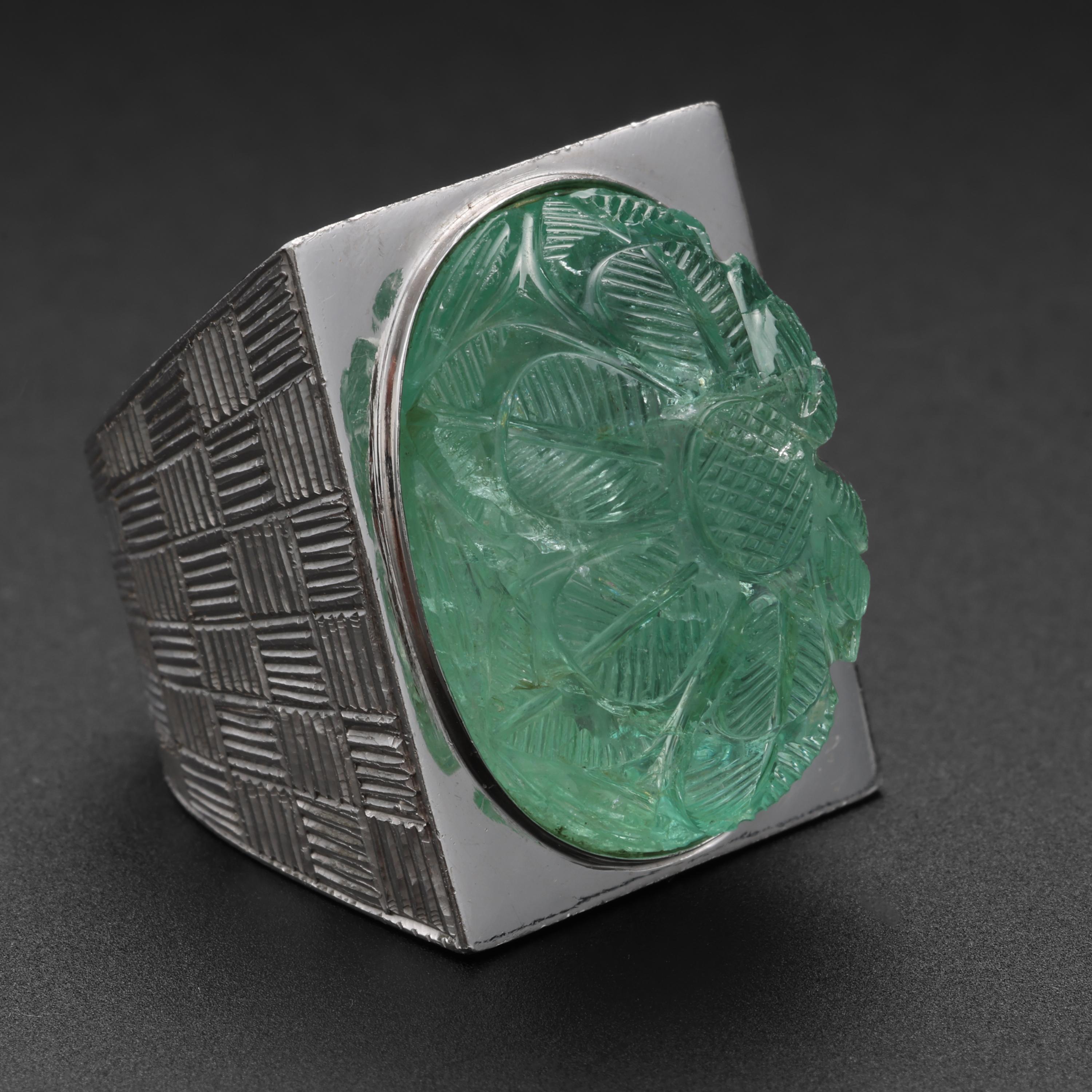 A massive, absolutely staggering 42 carat impeccably hand-carved natural Russian emerald that is so transparent it appears to be glass is the stunning focalpoint of this wildly original and incredibly impressive ring. 

The angular, modernist
