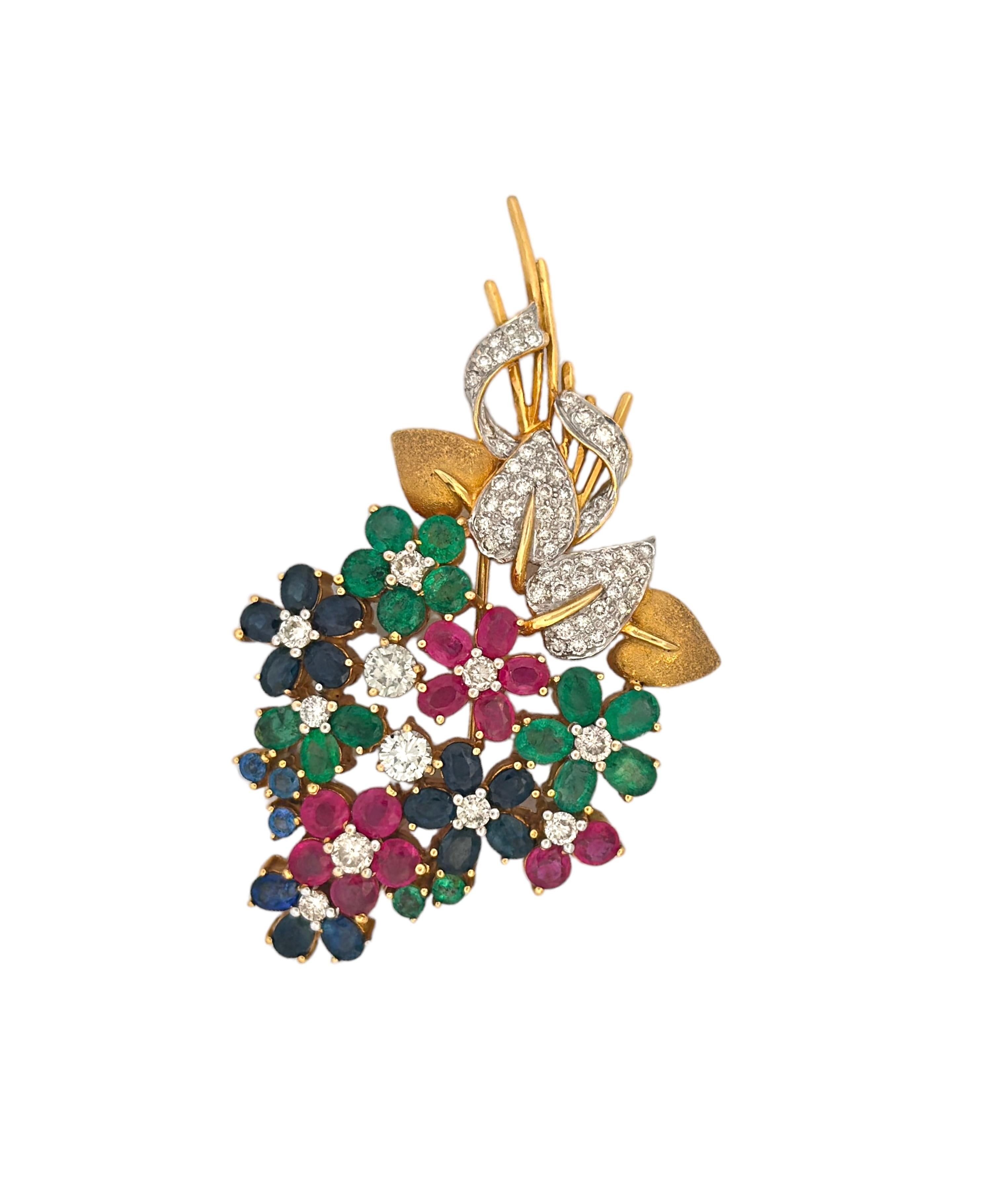Journey back in time to the opulent 20th century with this exquisite Emerald, Ruby, Sapphire, and White Diamond Bouquet Brooch. A harmonious medley of gemstones adorns this vintage masterpiece, with vibrant emeralds, deep rubies, brilliant
