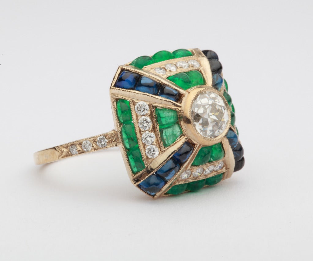 Set with central old-mine-cut diamond weighing  0,73 carats VVS clarity, top crystal color, 22 brilliant-cut diamonds weighing 0,31 ct., 12 cabochon sapphires weighing approximately 2,34 ct. and 20 cabochon emeralds weighing 2,18 ct. Mounted in 18K