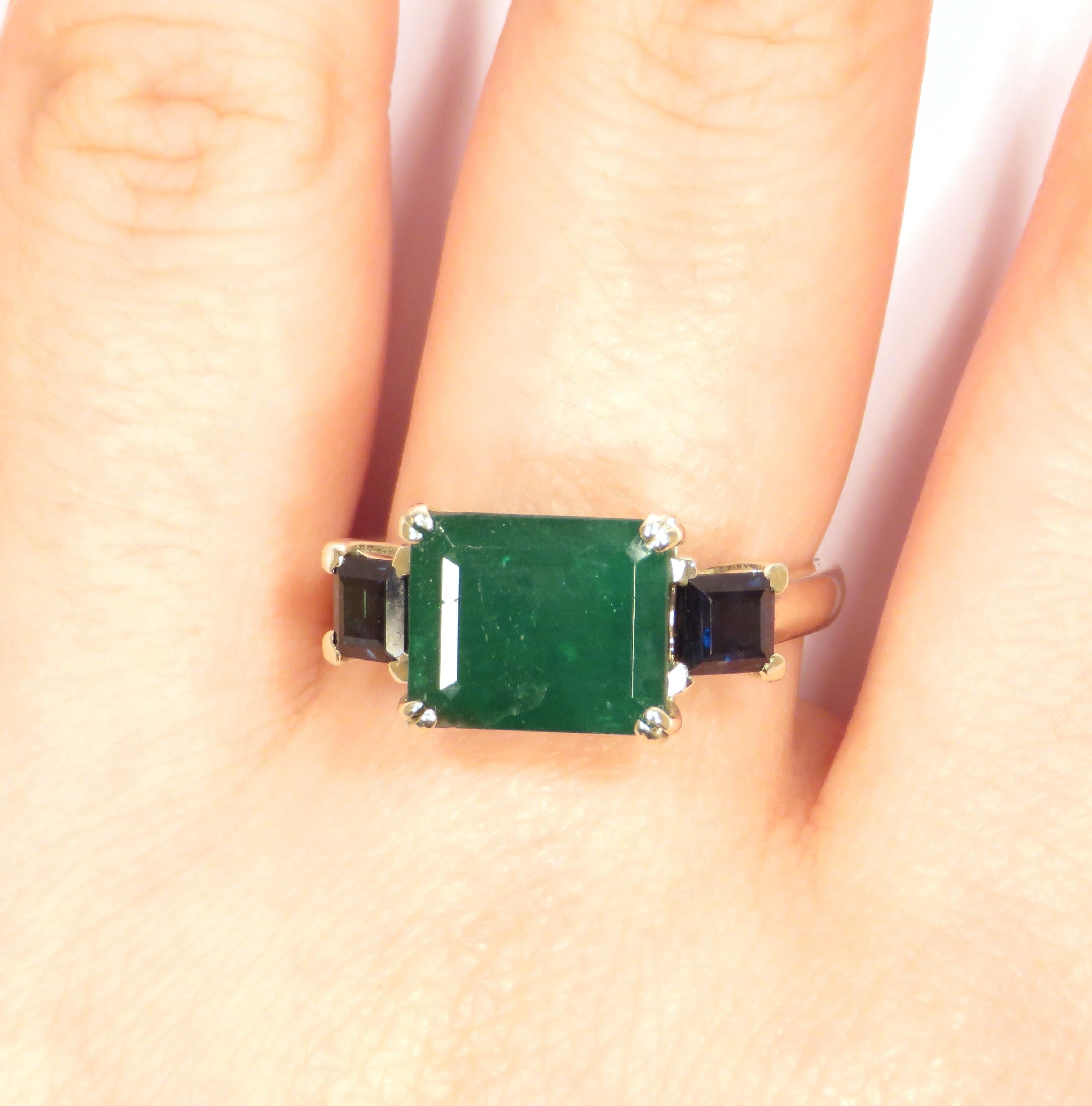 Engagement ring showcasing a beautiful emerald with 2 sapphires set in 9 karat white gold. The emerald size is 10,40 x 8,60 mm - 0.4094 x 0.3385 inches. US finger size is 7 1/2, French size 56, Italian size 16, the ring can be resized to the