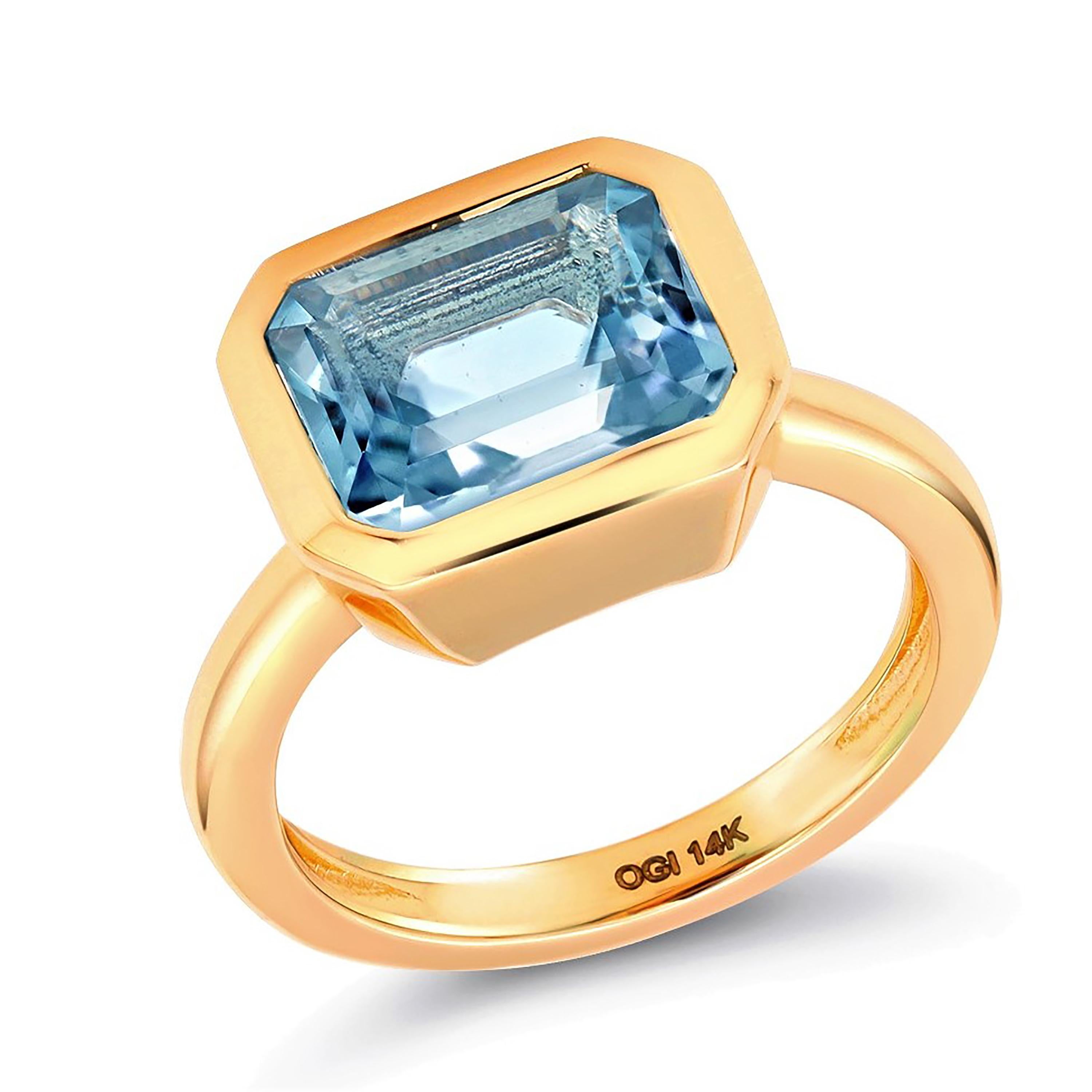 Fourteen karats yellow gold raised bezel dome cocktail ring
Blue and brilliant emerald cut shaped aquamarine weighing 3.14 carats   
Aquamarine hue color: sky blue                                                                 
Ring size 6.5 In
