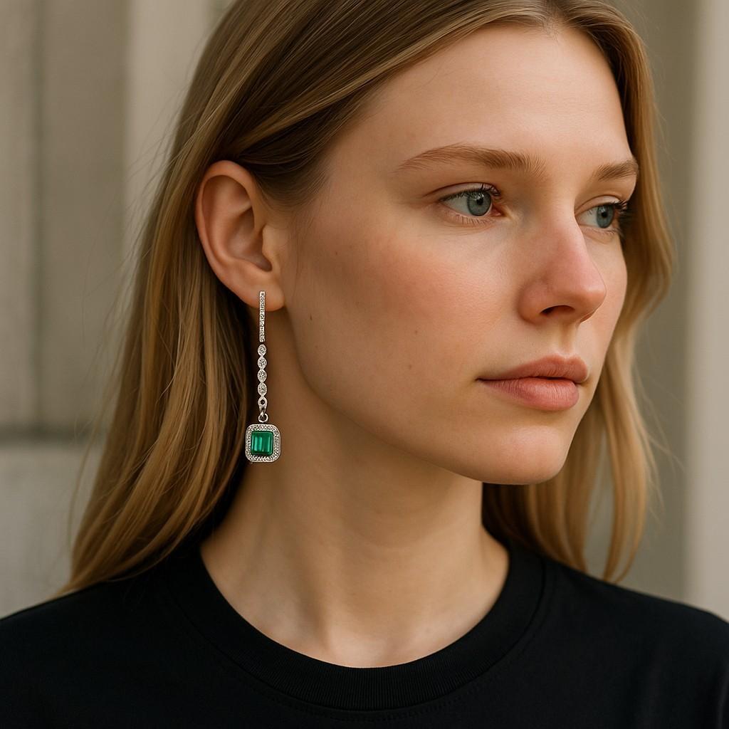 Voici nos exquises boucles d'oreilles faites à la main et fabriquées à New York : les boucles d'oreilles Lariat en forme d'émeraude, avec halo de diamants. Ces superbes boucles d'oreilles sont en or blanc de quatorze carats et mettent en valeur des