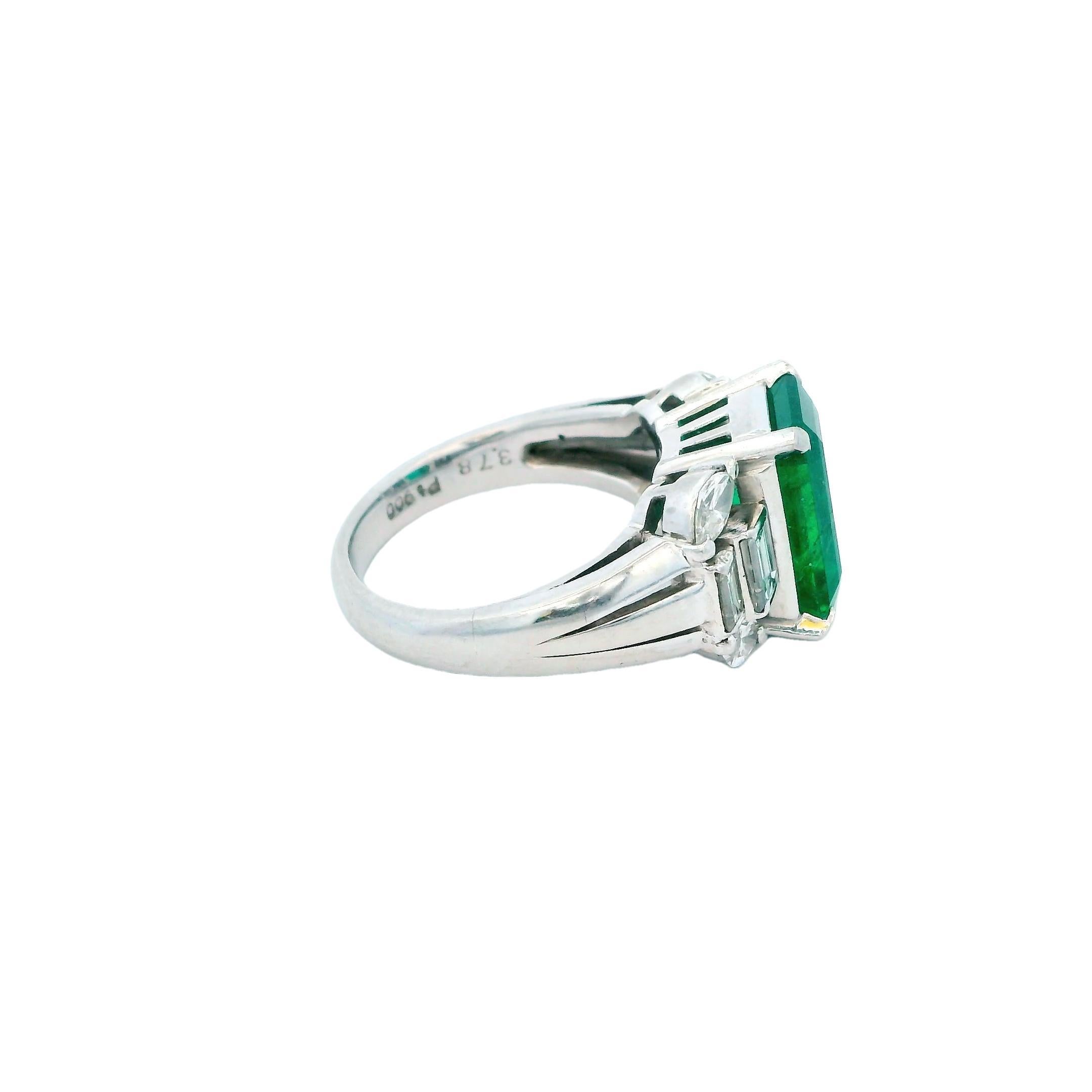 An exquisite emerald ring from the 21st Century.

This stunning platinum ring features a captivating emerald-cut emerald as its centerpiece. The vibrant green stone is securely held by four prongs, allowing light to enhance its natural beauty.