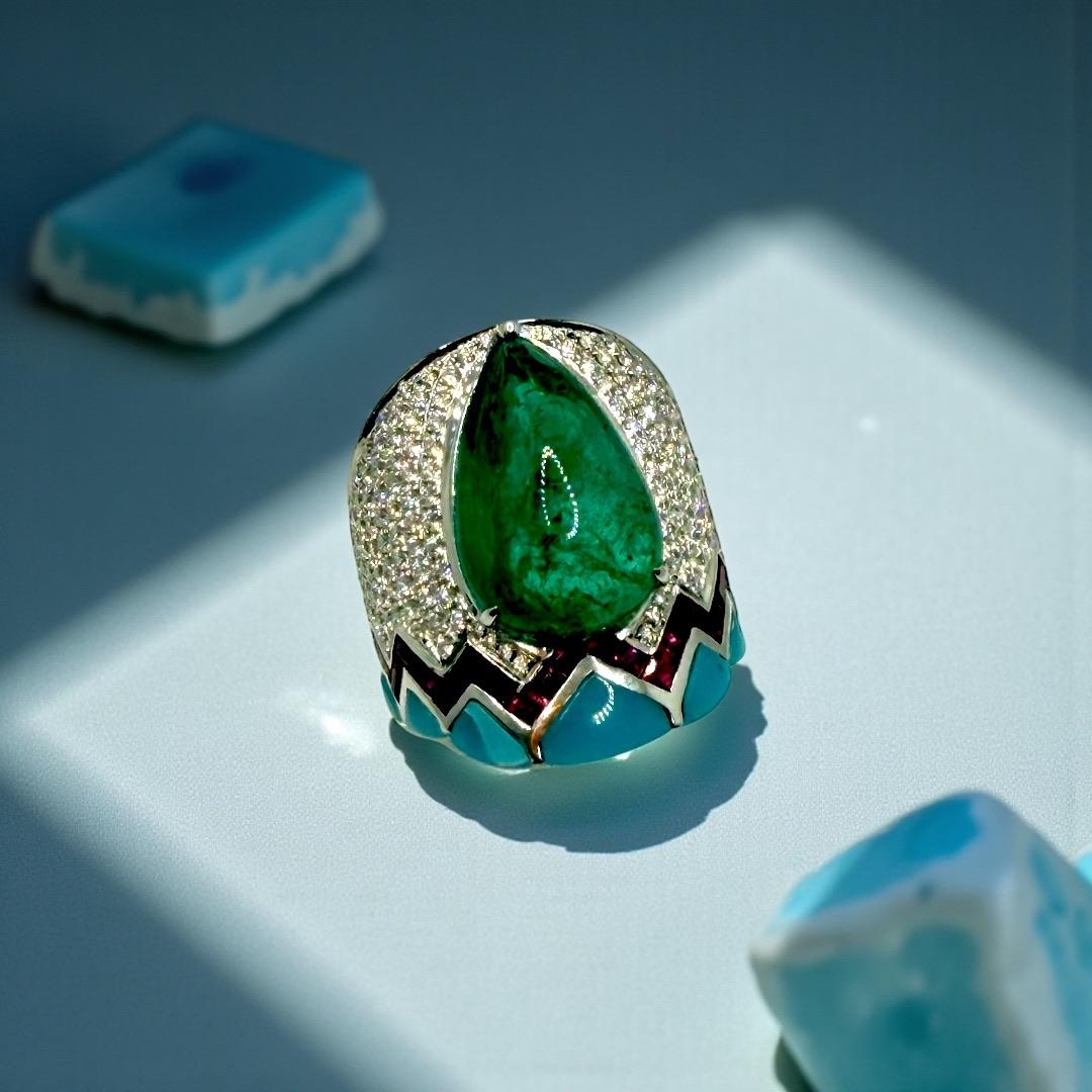 Dieser Ring ist ein kühnes Fest der Farben, der Handwerkskunst und des skulpturalen Designs. In seinem Zentrum befindet sich ein 10,40ct sambischer birnenförmiger Cabochon-Smaragd, der mit einer reichen, natürlichen Tiefe und einer unverwechselbaren