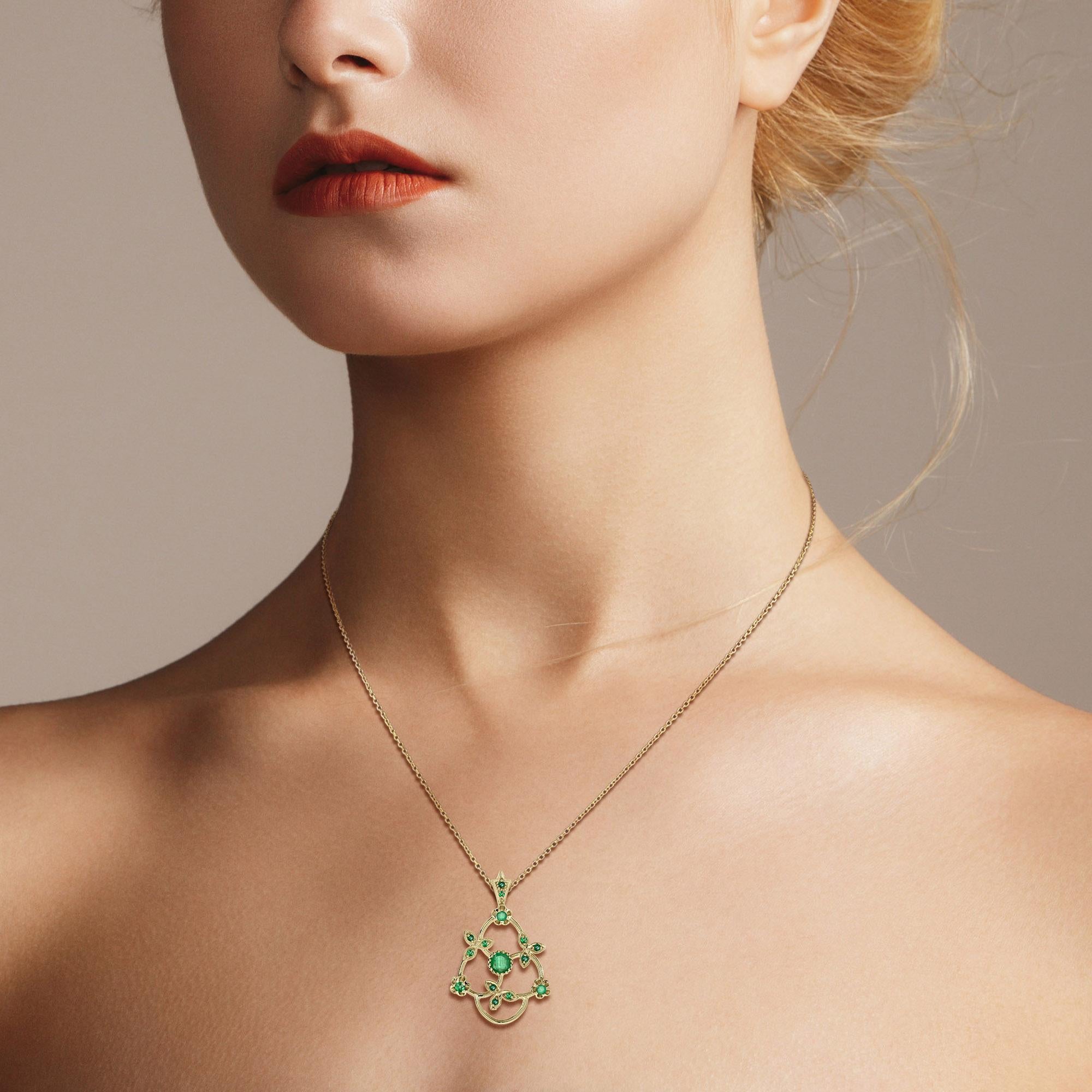 This fine and impressive emerald antique pendant has been crafted in 9k yellow gold. The pendant displays a central feature round-cut emerald accented with smaller emerald set in an openwork floral and leaves motif frame. This piece is perfect to
