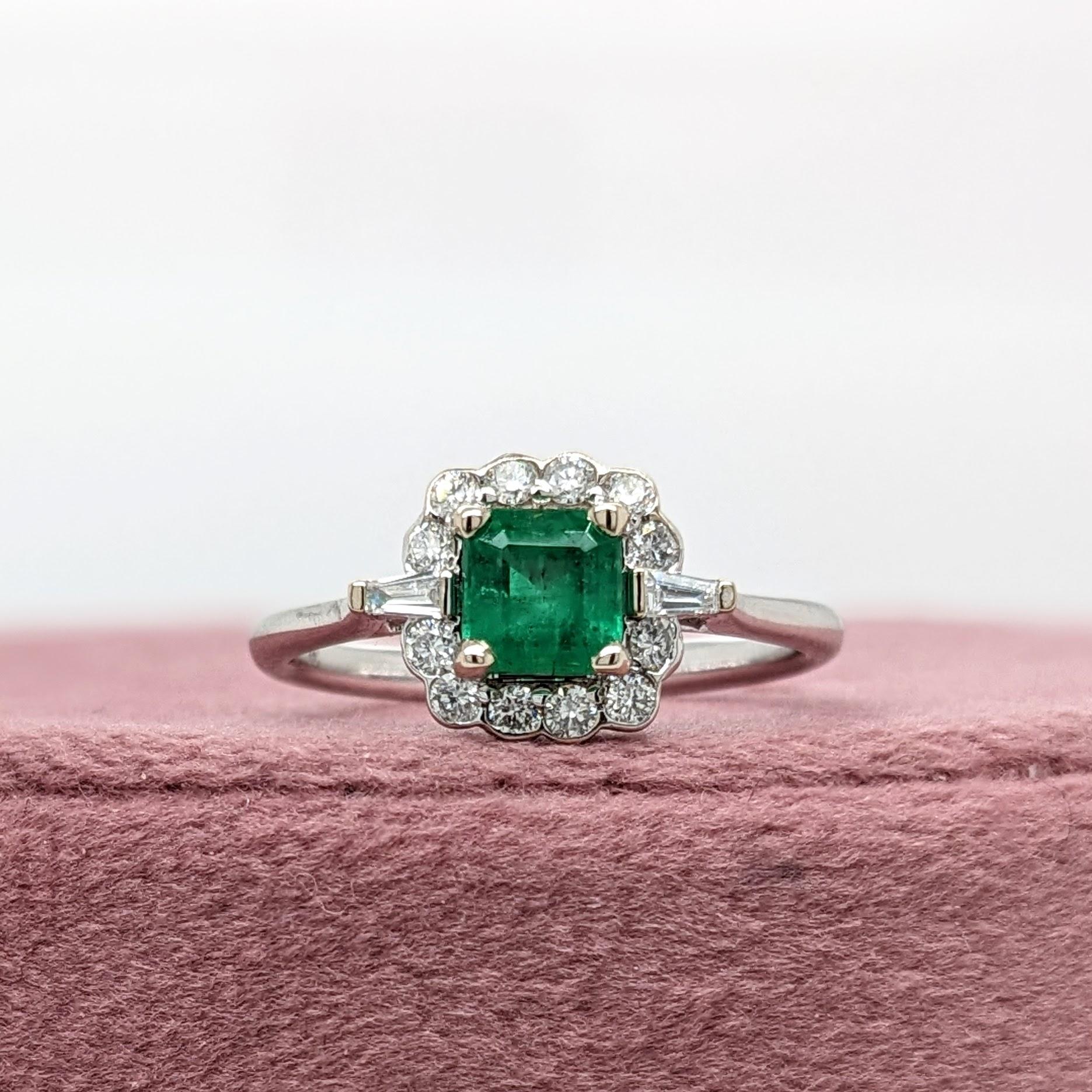 This lovely balanced ring design flaunts a gorgeous Zambian Emerald with an incredible grass green hue. It's a great size for a daily accessory and looks stunning seated in a scalloped halo of diamonds, with two tapered baguette diamonds that create
