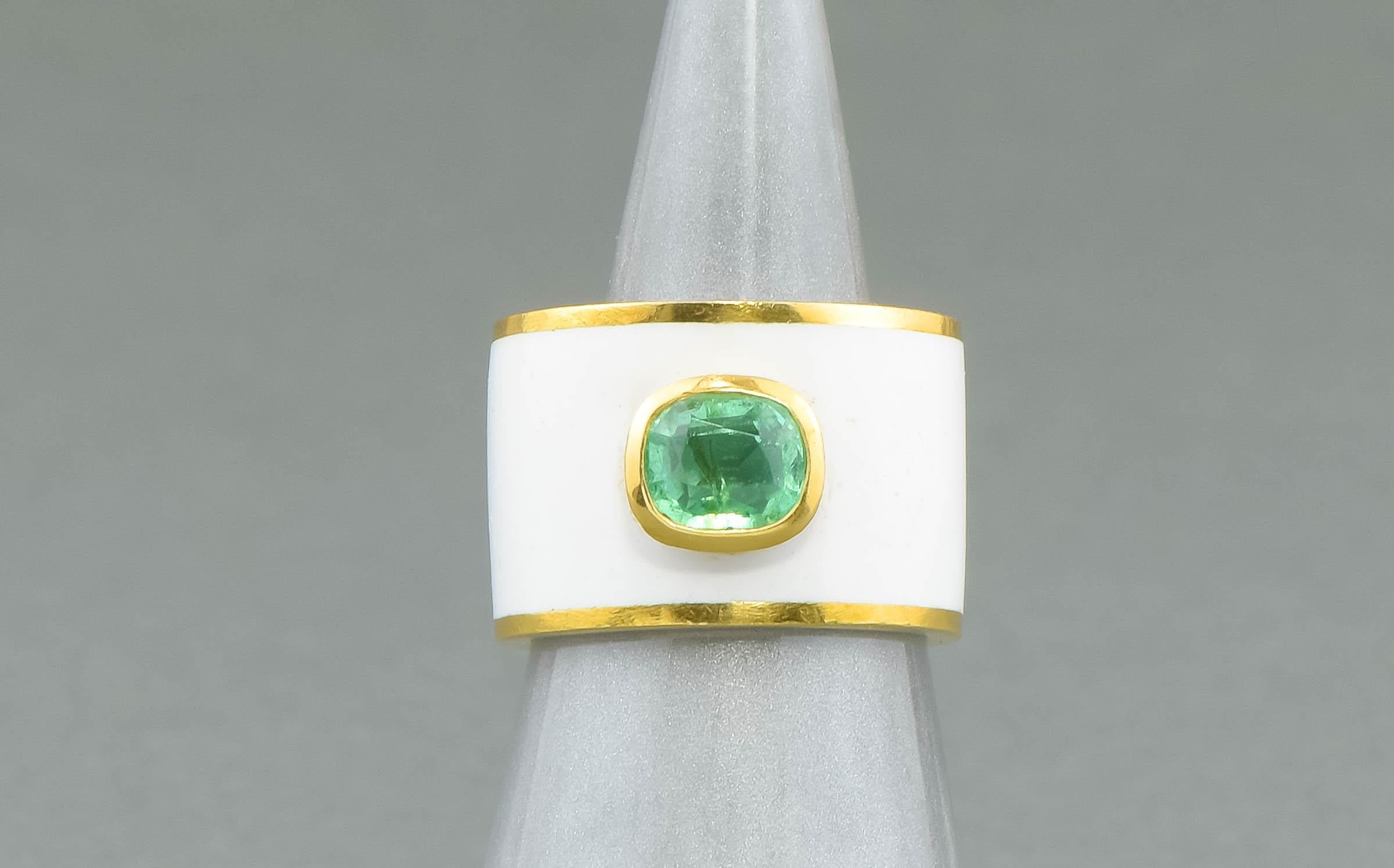 Crafted of buttery solid yellow gold marked as 14K but testing a bit higher for me, this unusual ring features a cushion shaped emerald bezel-set atop a wide and heavy enameled band. The bright spring green of the emerald absolutely 