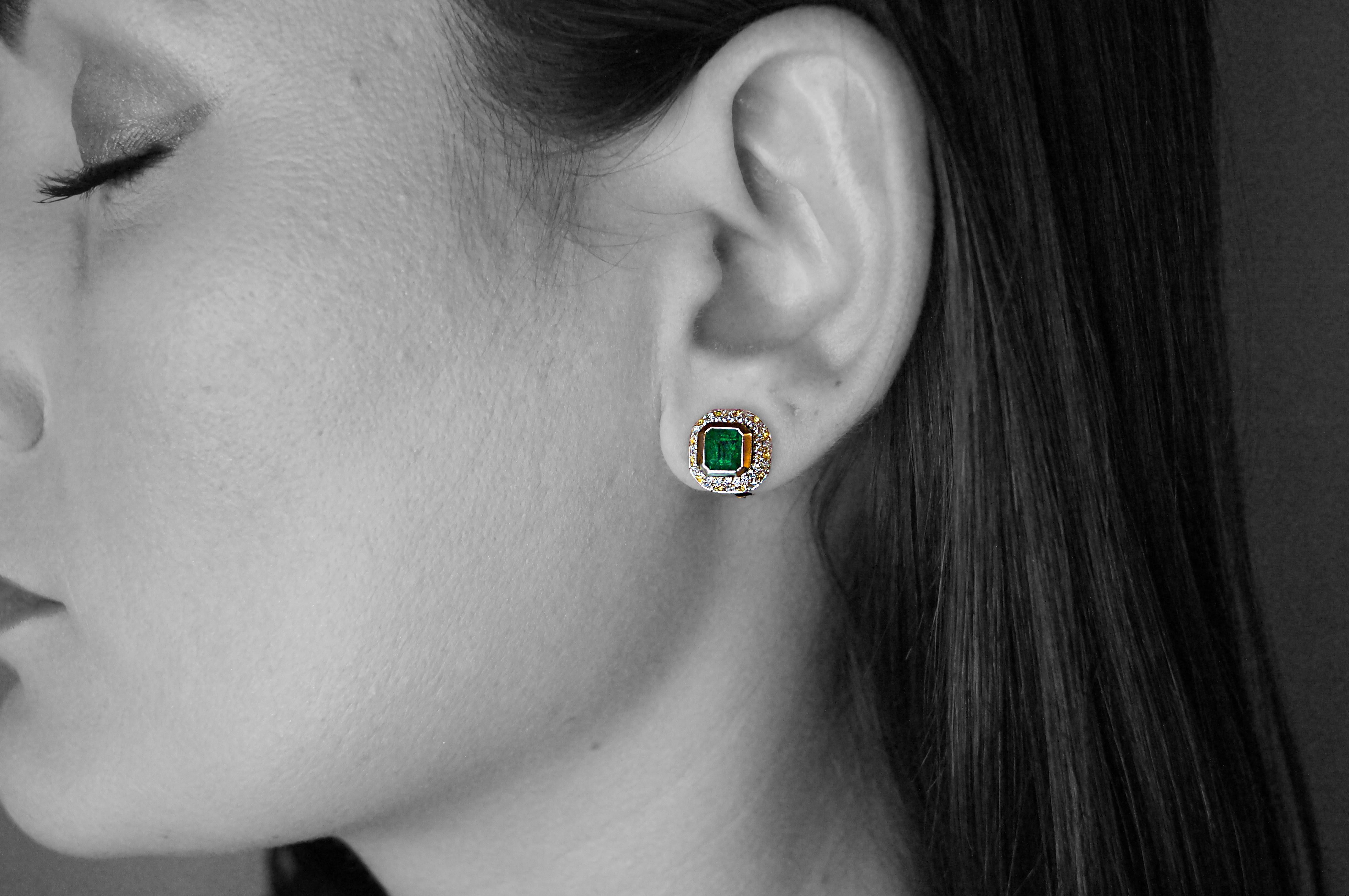 Questi fermagli per orecchie di alta qualità e bellezza sono realizzati in oro bianco da 18 carati e presentano una magistrale incastonatura in oro giallo da 18 carati che circonda due vivaci smeraldi verdi di alta qualità con taglio a smeraldo.