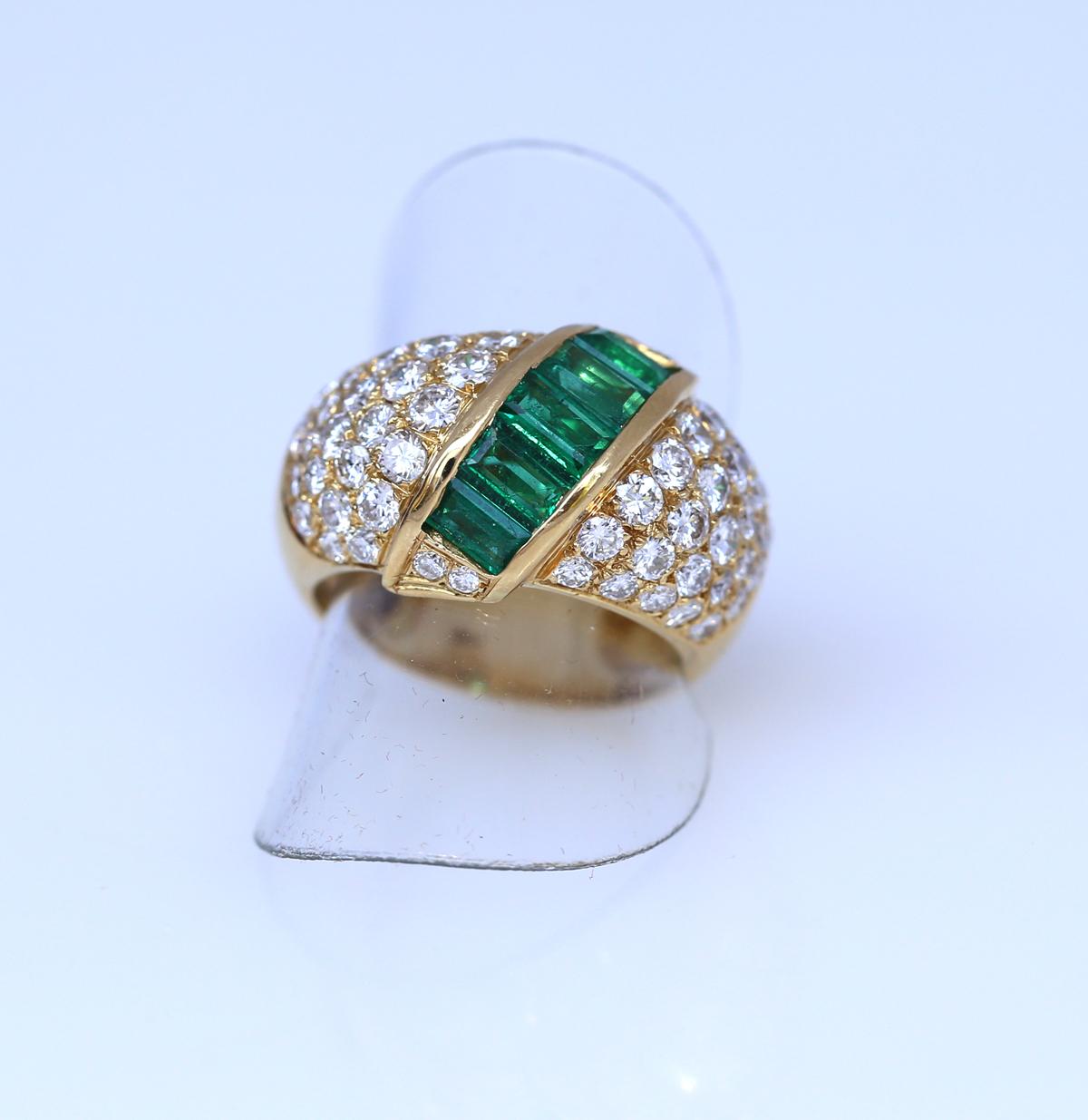 A Fine 18K Gold Diamond and Emerald Cocktail Ring. Designed as a bombe band with the crown centred by a diagonal row of fine quality Emeralds on a ground of pave-set, fine Diamonds. Approximately  60 Diamonds weighing  3.5Ct in total. Stamped on the