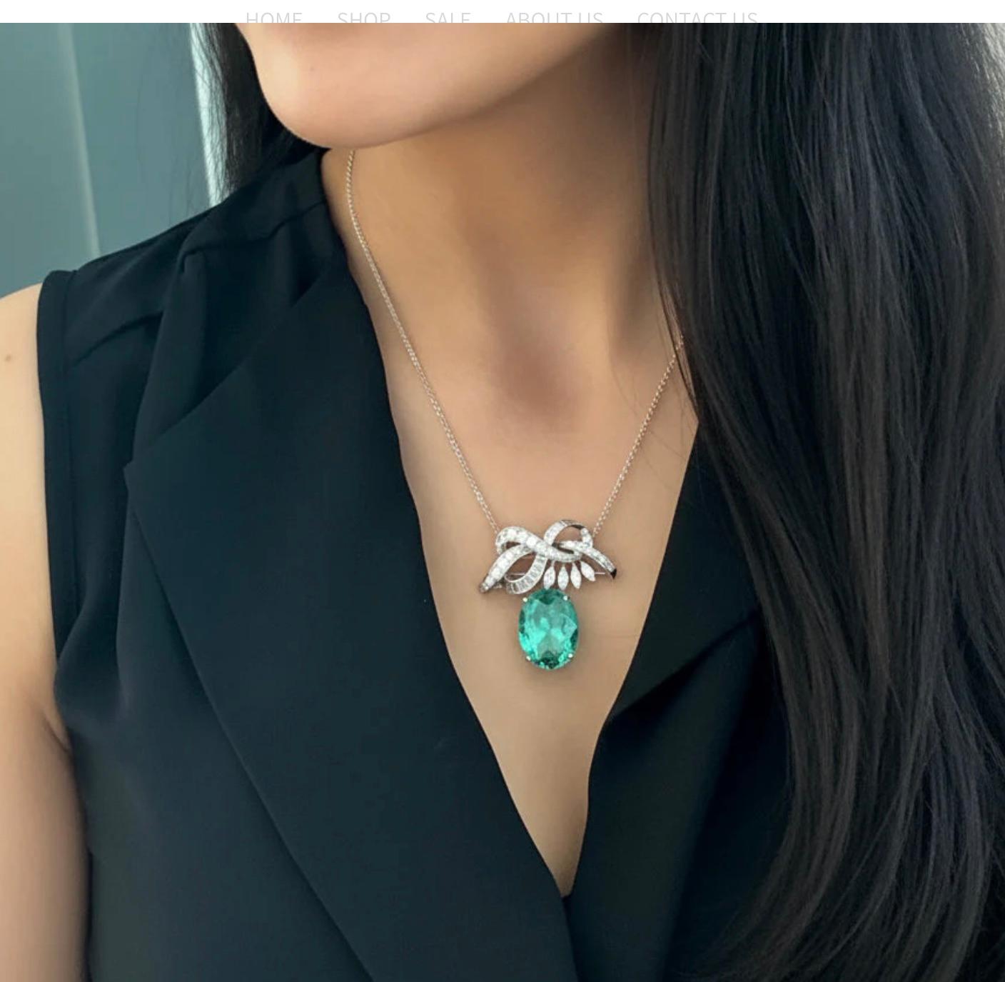 Eine exquisite Brosche/Anhänger-Halskette mit einem natürlichen kolumbianischen Smaragd im Ovalschliff mit einem Gewicht von 16,16 Karat, eingefasst in eine Brosche mit Bandmotiv. Das Band ist mit spitz zulaufenden Diamanten im Baguetteschliff,