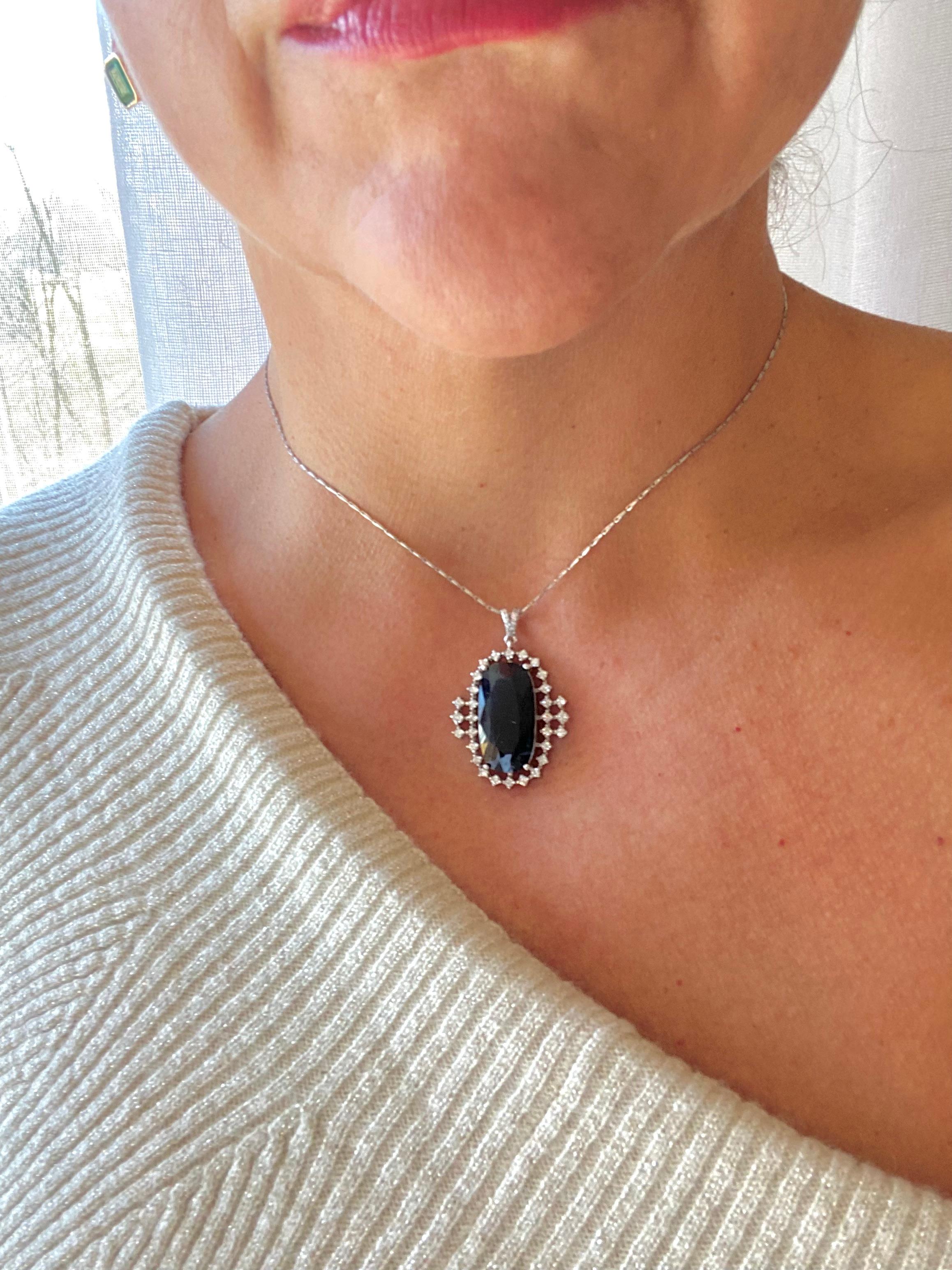 A Simple and Timeless Drop Pendant Showcasing a Large 22.57 Carat Midnight Blue Sapphire, Antique Cut Surrounded by a Row of Round Diamonds. The Solitaire Pendant is Made of Solid 18K White Gold. 
Primary Stones: Natural Sapphire 
Shape or Cut: