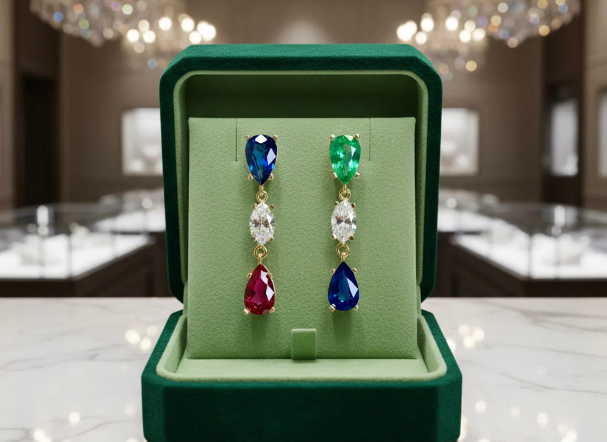 Ces extraordinaires boucles d'oreilles pendantes sont composées de saphir bleu de Birmanie, d'émeraude de Colombie d'un vert intense, de rubis d'un rouge éclatant et de diamants étincelants. Toutes les pierres précieuses de couleur naturelle sont