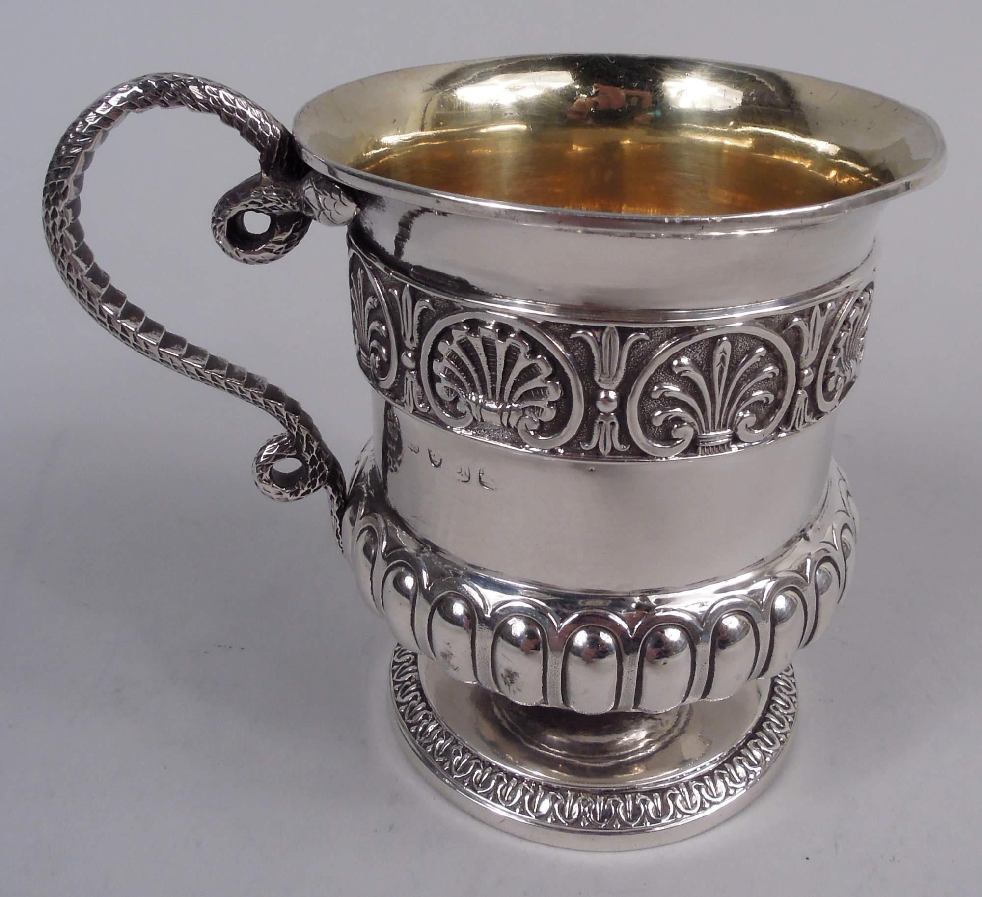 George III sterling silver baby cup. Made by Rebecca Emes & Edward Barnard in London in 1816. Campana urn bowl with cast palmette and shell border; raised foot with cast leaf-and-dart border. Cast two-headed snake handle. Gilt-washed interior.