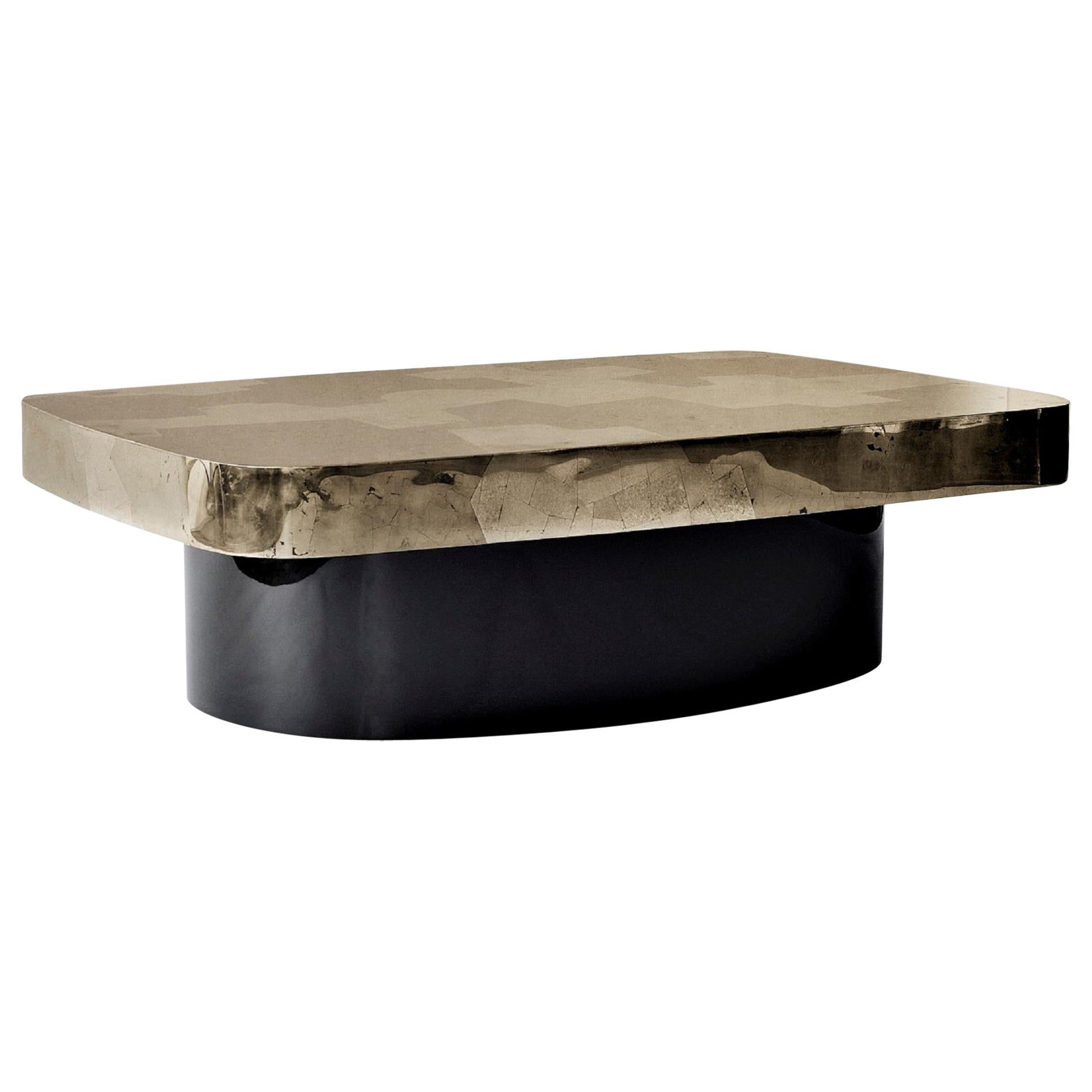 The Emil coffee or cocktail table features a hand-laid silver and golden pyrite top in a stunning, Brutalist-inspired design, supported by a glossy black lacquered wood base.