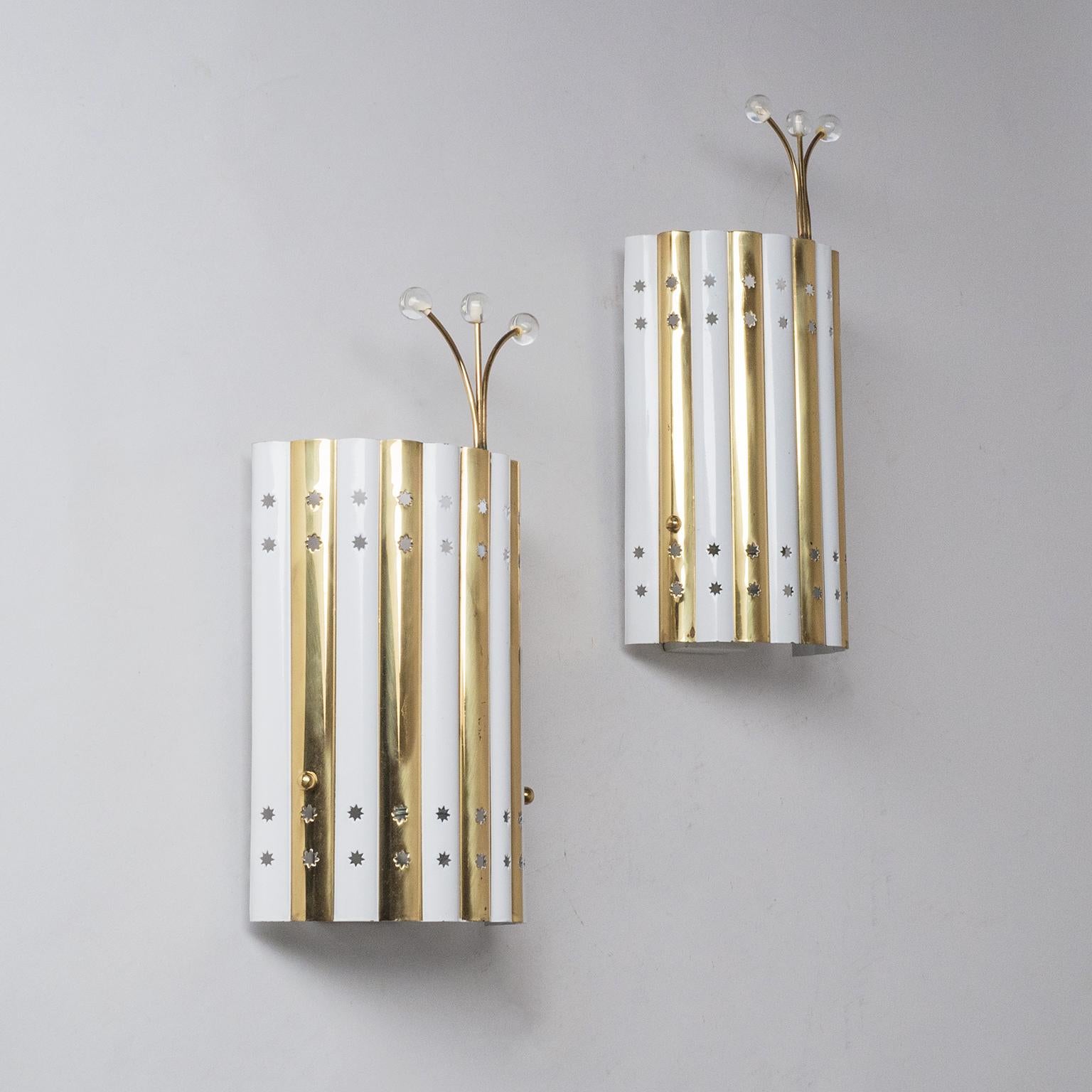 Very rare pair of brass sconces attributed to Emil Stejnar, 1950s. Made of sculpted sheet brass with alternating white lacquered stripes these unique wall lights have four rows of star shaped cutouts and are topped off with charming glass adorned
