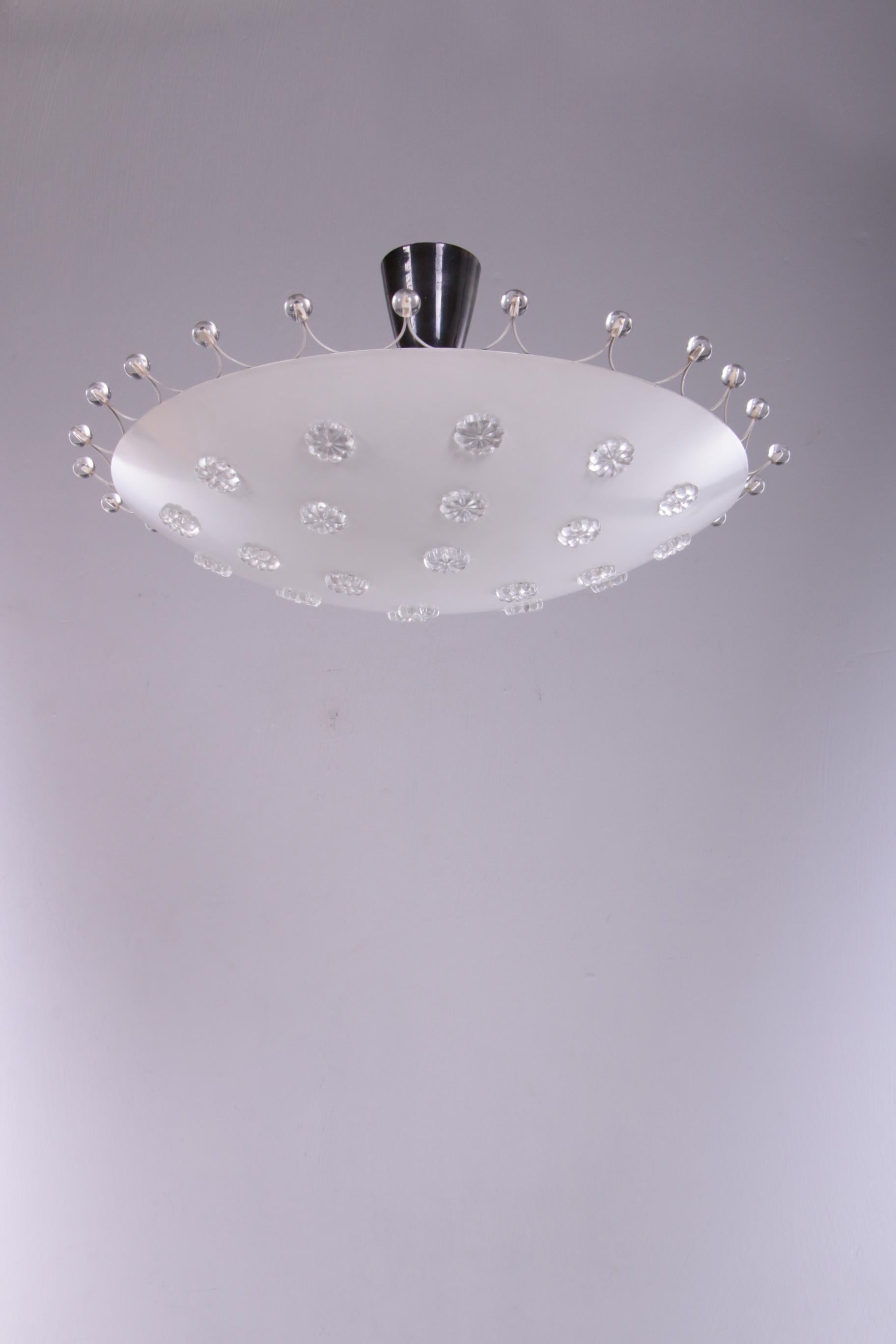Emil Stejnar ceiling lamp for Rupert Nikoll, Austria 1950s


Large ceiling lamp by Emil Stejnar for Rupert Nikoll, Austria.

White steel perforated dish with glass flowers in the holes, white wire steel rim with glass balls, 4 E27 fittings.