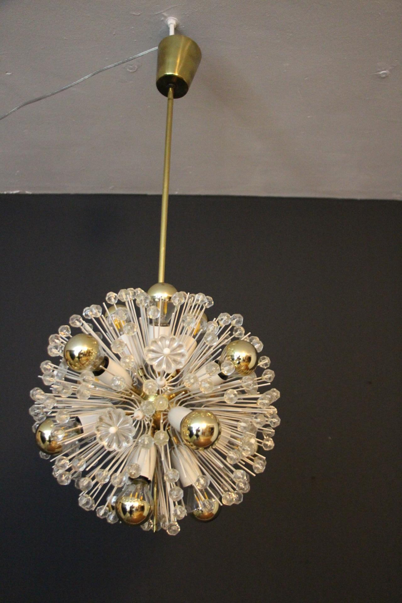 This spectacular Sputnik Chandelier looks like a flowers explosion.It features a multitude of brass rods ending with bulbs or clear crystal flowers. Each rod is directly fixed on its polished brass central sphere . Its rods are ending with delicate