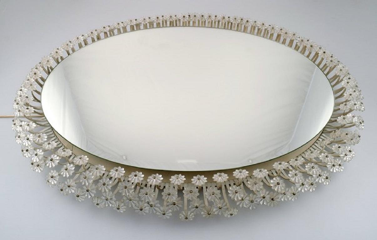 Emil Stejnar for Rupert Nikoll. 
Illuminated mirror rounded with three rows of crystal flowers with brass flower stalks. Mid-20th century.
The mirror plate measures: 67 x 48 cm.
Total dimensions: 82 x 63 cm.
In excellent condition.