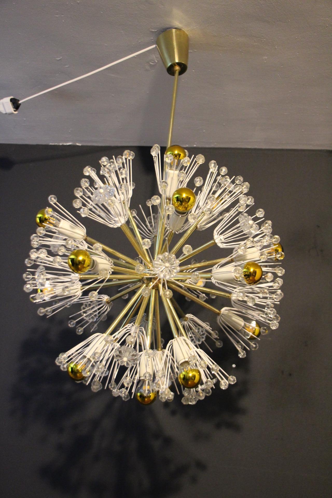 Ce spectaculaire lustre Sputnik ressemble à une explosion de fleurs et se compose d'une multitude de tiges en laiton terminées par des bulbes ou des fleurs en cristal clair. Chaque tige est directement fixée sur sa sphère centrale en laiton poli .
