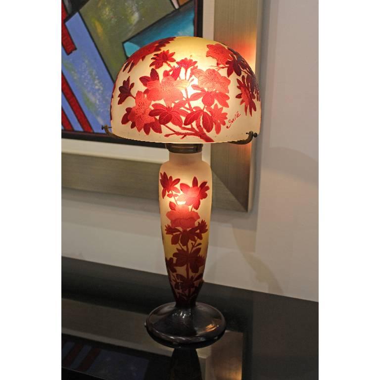 Authentic table lamp by Emile Gallé depicting flowers and foliage, with a red color layer over an opalescent yellow colored glass.
Signature: 