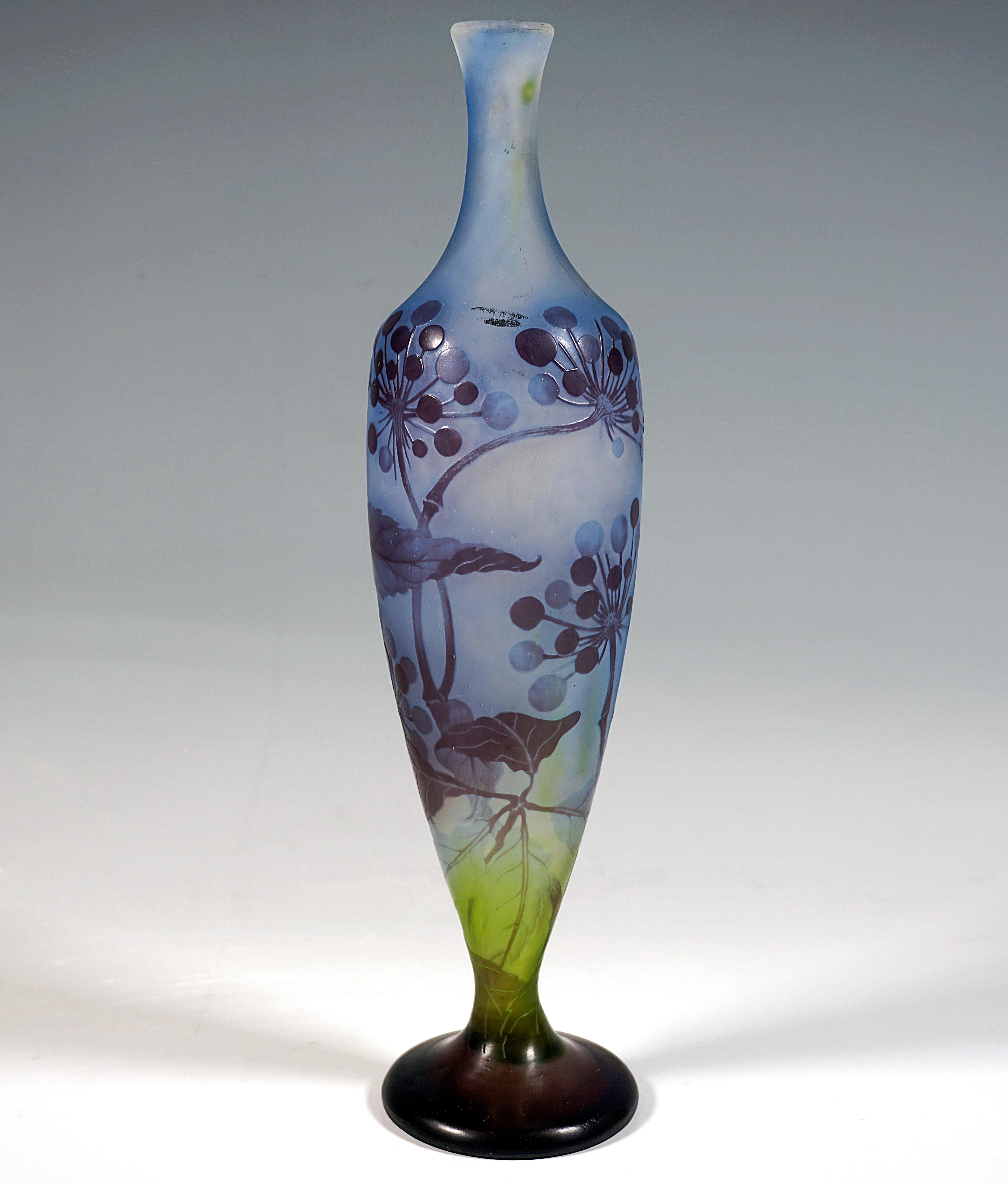 Schlanker, balusterförmiger Vasenkörper auf separatem Sockel, sich konisch nach oben verbreiternd und dann wieder verjüngend zu einem schlanken Hals mit ausgestelltem Rand, farbloses Glas mit blauen und grünen Pulvereinschlüssen, violett überfangen,