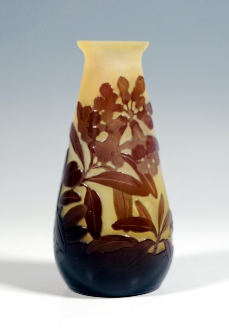 Vase in the form of a flacon: slightly bulbous body, tapering towards the top, narrow opening, widening to the flared rim of the mouth. Colorless glass with white and yellow colored powder melts, overlaid in brown on the outside, floral decor with