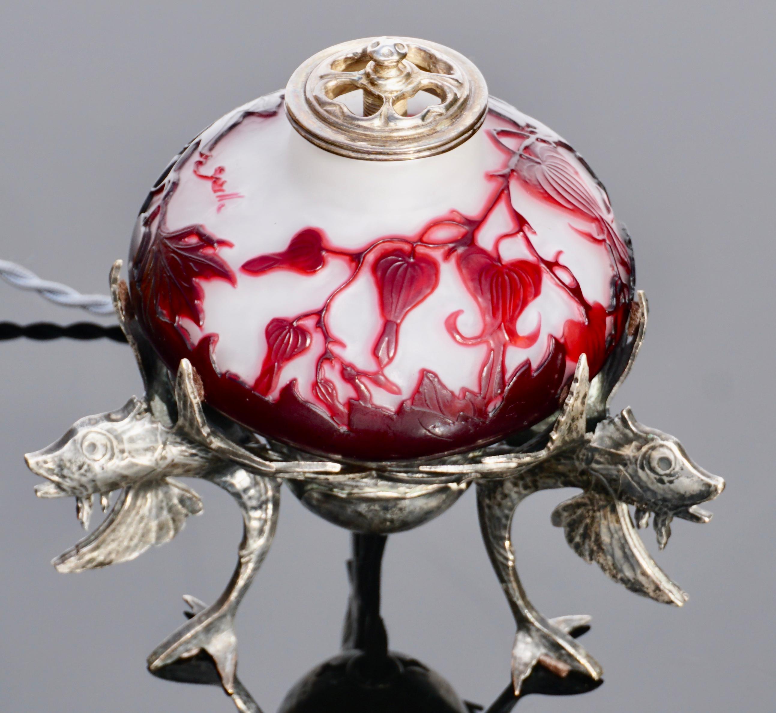 Emile Galle French Art Nouveau nightlight has glass body with red cameo leaf and flower decoration against a creamy white background. The glass body is housed within a silver plated frame with flying fish feet with wings supporting the glass body. A