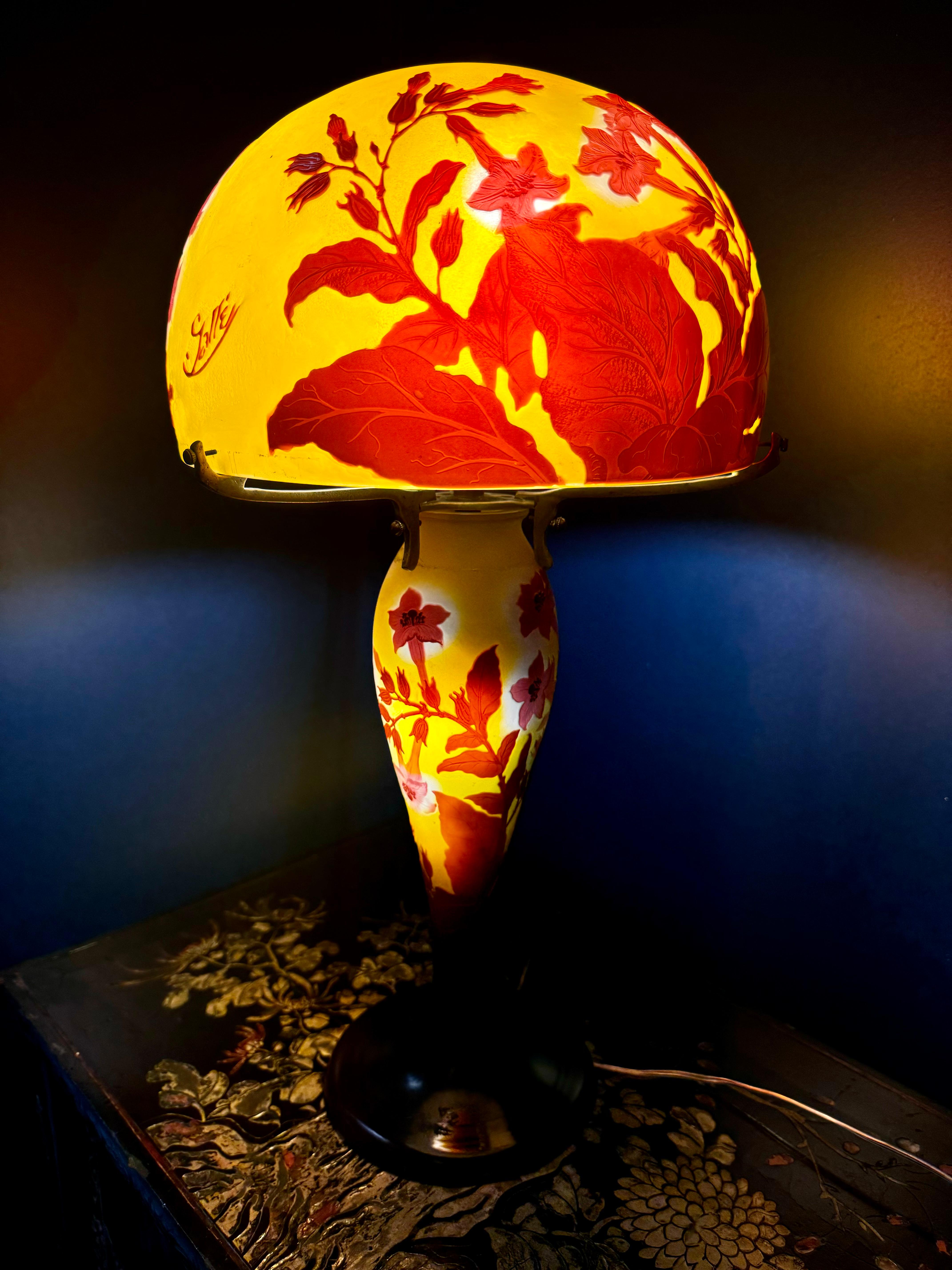 Rara Lámpara Francesa Antigua Galle Firmada Cut-Cameo con Pantalla Original Galle Firmada Cut-Cameo, en Colores Rojo y Amarillo Atardecer.
La lámpara presenta un diseño magistral con una vibrante paleta de tonos rojos y amarillos, que se mezclan a