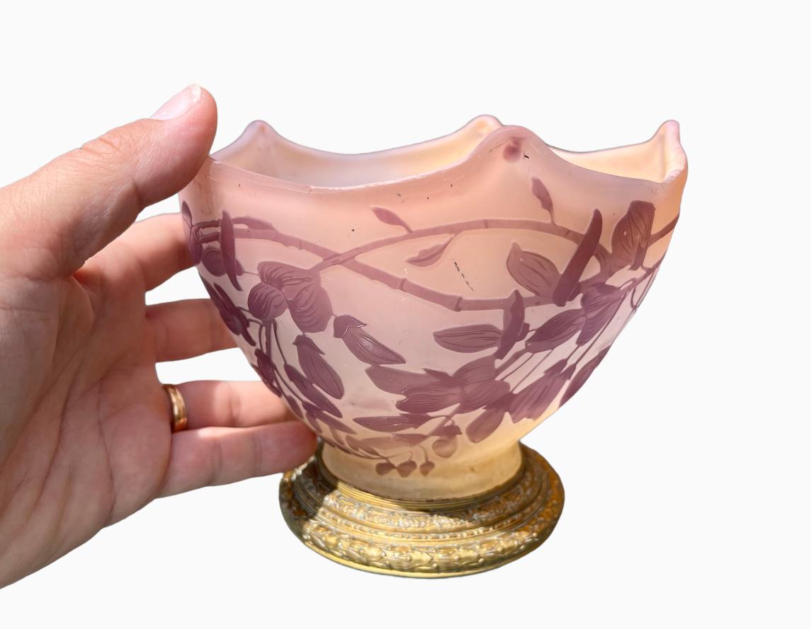 Vase oder Becher aus geschmolzenem Glas, verziert mit lila Blumen auf weißem/rosa Hintergrund. Diese Vase ruht auf einem runden Sockel aus vergoldeter und ziselierter Bronze. Signiert 