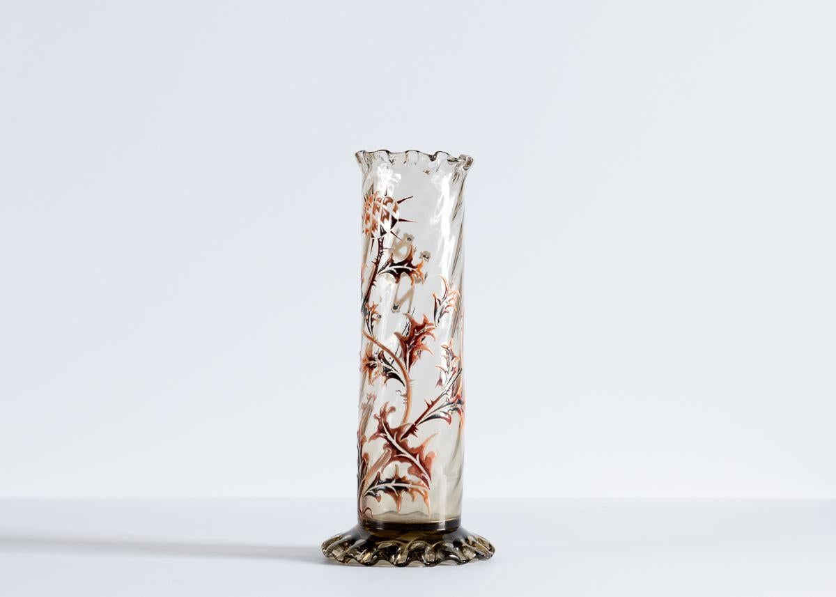 This trio of cylindrical, diagonally ribbed vases comes from one of the Art Nouveau's great masters, the French artist Émile Gallé. The pieces, executed in one his preferred mediums, enameled glass, depict thistles in muted reds and browns, and rest