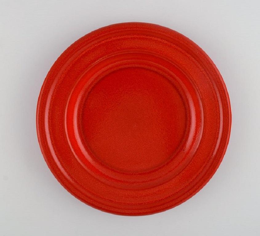 Emile Henry, France. Eight lunch plates in glazed stoneware. 
Beautiful glaze in shades of red. 
Mid-20th century.
Measure: Diameter: 20 cm.
In excellent condition.
Since 1850, Emile Henry has established a worldwide reputation for