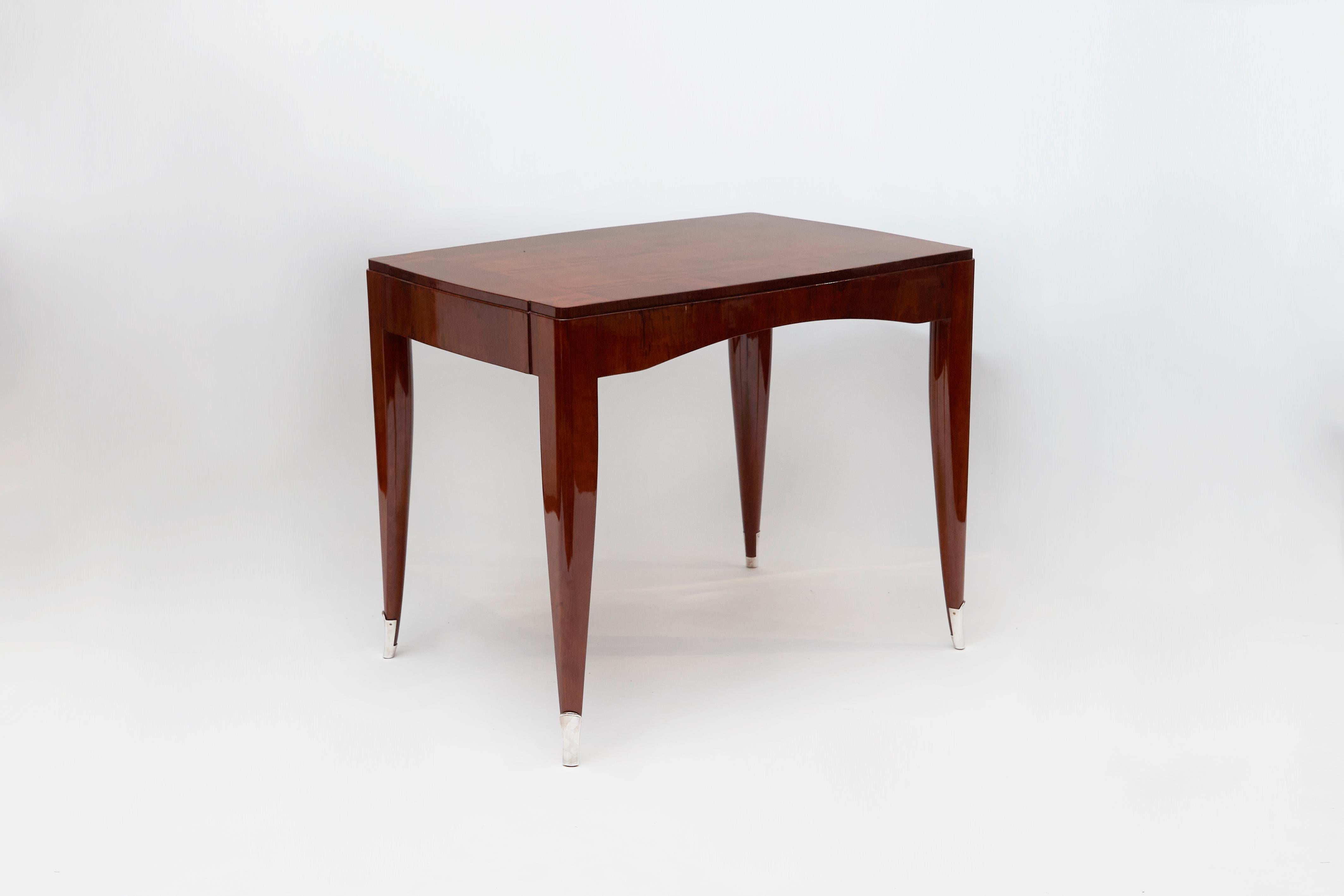 This rare writing table in polished mahogany and silvered bronze is marked by E´mile-Jacques Ruhlmann's signature aesthetic motifs, manifest in its set of flared and tapered legs, and juxtaposition of supple, living curves with others so subtle as