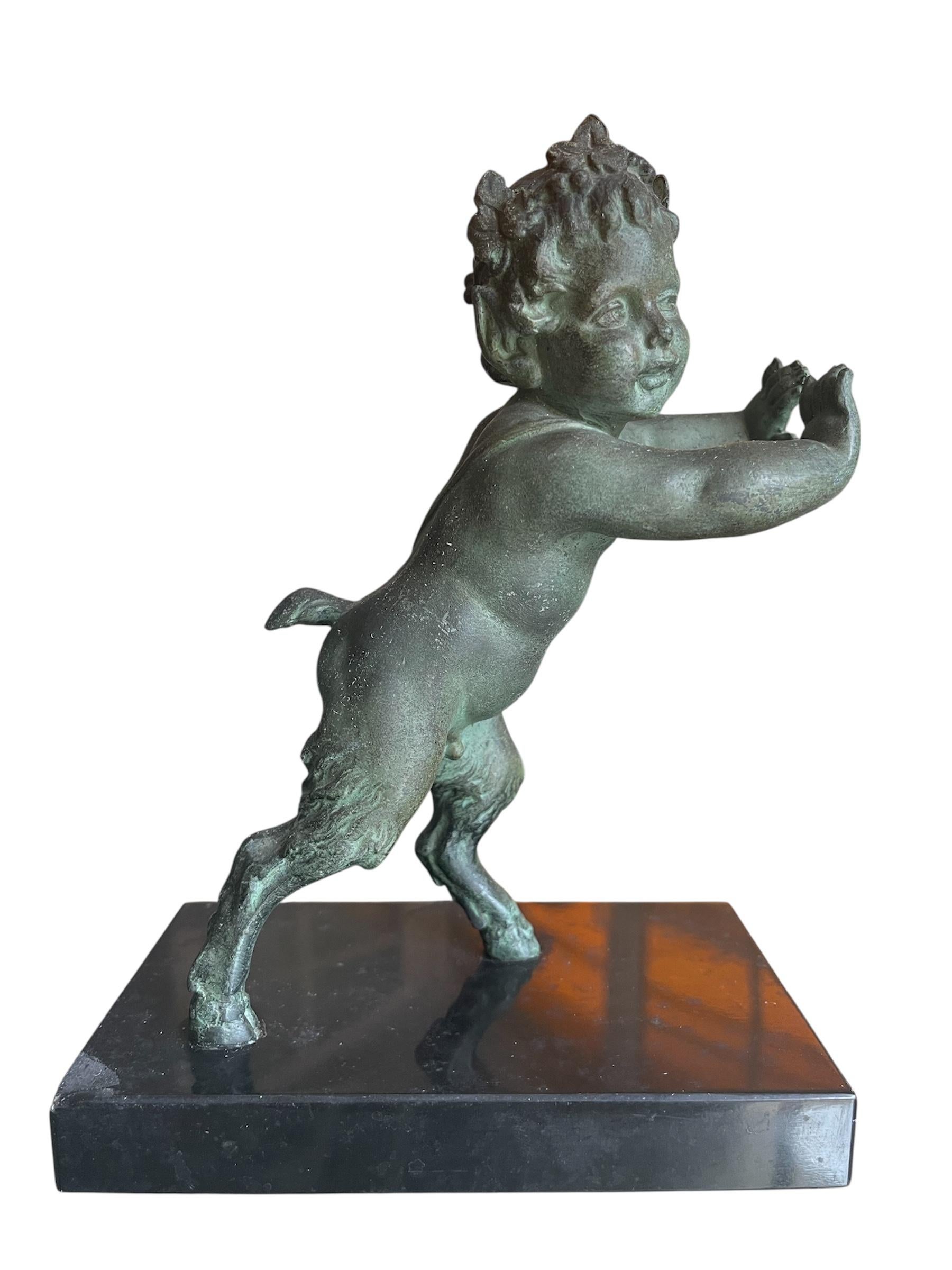 Pair of bookends in spelter and black marble representing on one side a young satyr and on the other a kid, each struggling to keep the books upright. They are signed on the bases with a point 