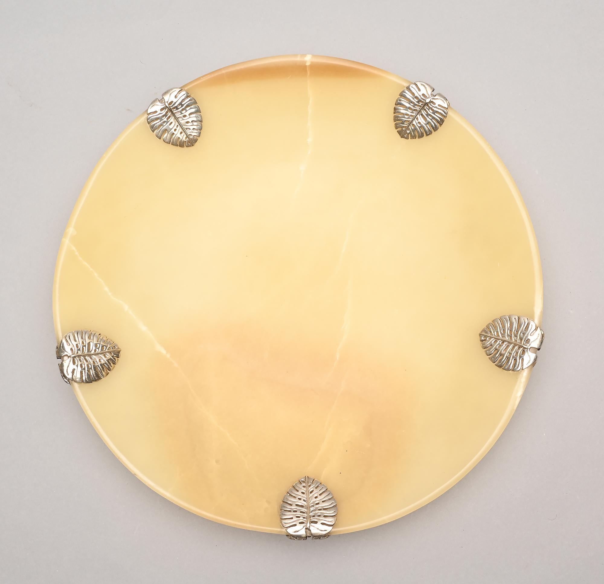 This elegant alabaster bowl with sterling silver ornamentation was made by Emilia Castillo. The bowl measures 14 inches in diameter and features five leaves, that I believe are philodendron, which are folded over the rim. Irregularities in the color