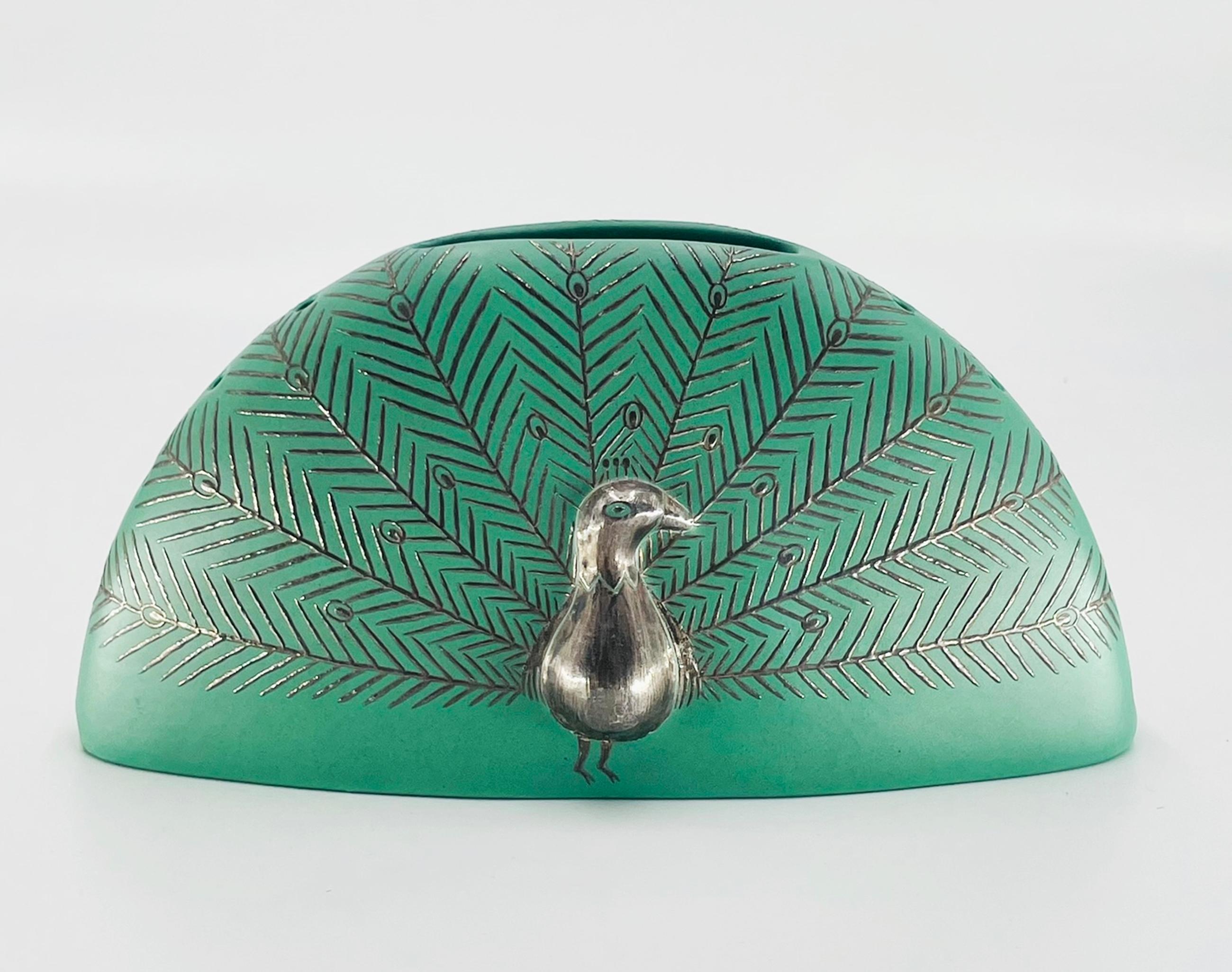 Charmant vase finement ouvragé, conçu et fabriqué à Taxco, au Mexique, par la célèbre orfèvre Emilia Castillo en 1998. La pièce présente le mélange de porcelaine et d'argent pur caractéristique de Castillo, représentant un motif de paon stylisé en