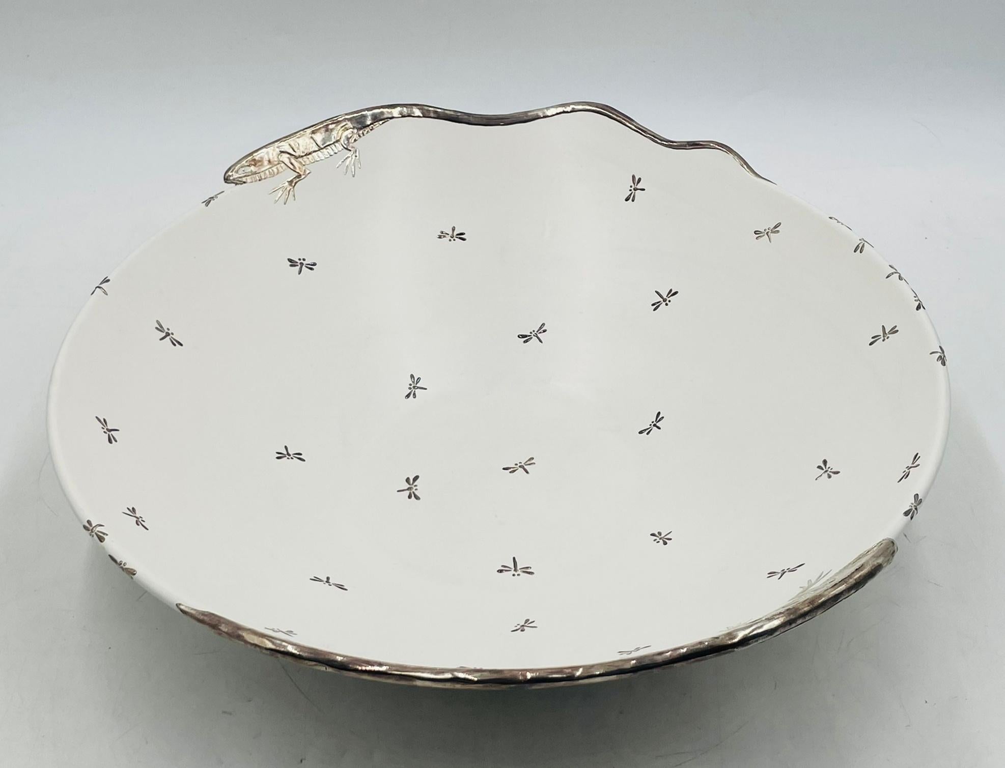 A remarkable large decorative bowl designed and handcrafted by Emilia Castillo in Taxco, Mexico, merging fine porcelain with intricate pure silver (plata pura) details.

The bowl’s surface is scattered with delicate silver dragonflies, while two