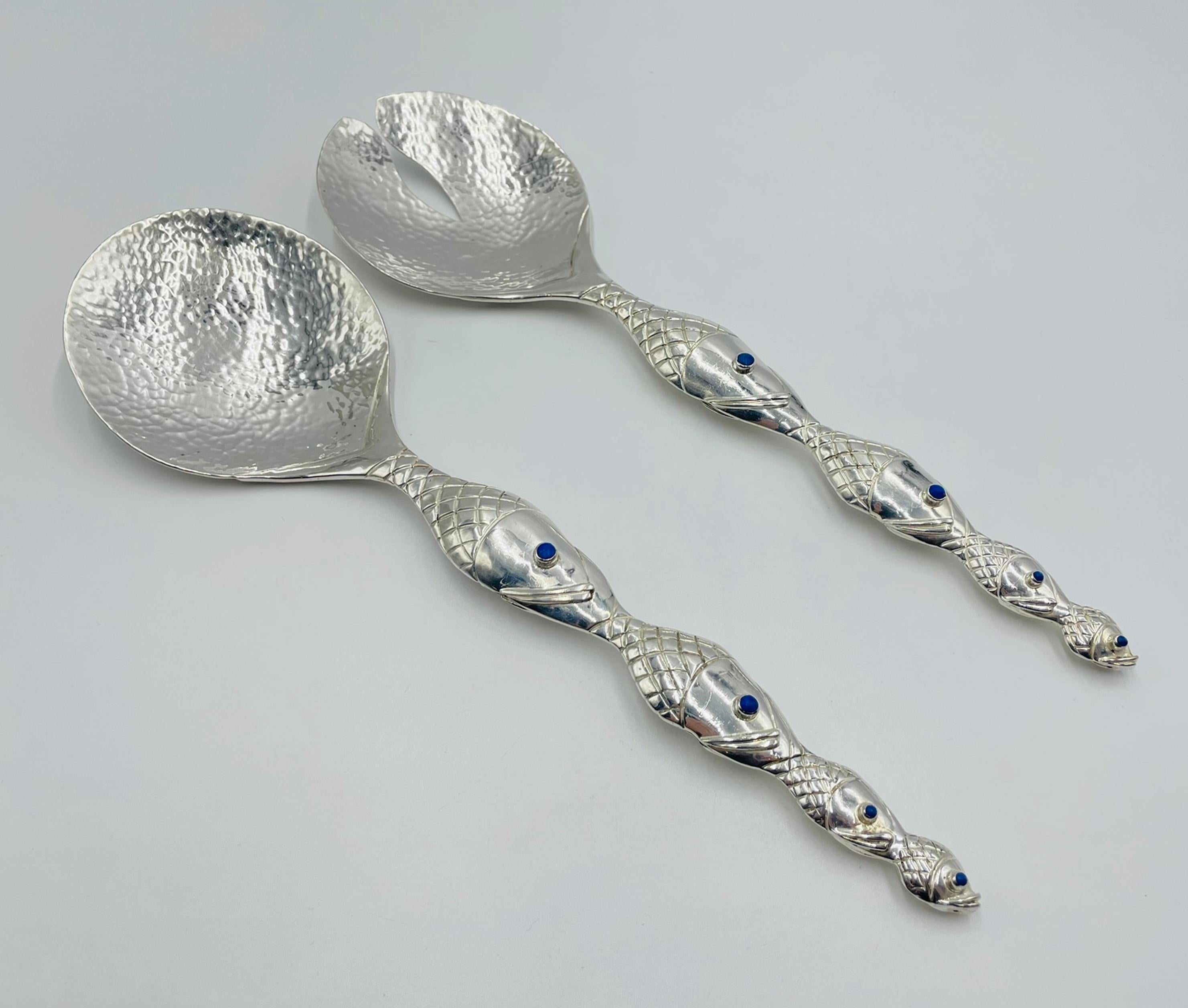 Ein auffälliges Paar handgefertigter Servierutensilien, entworfen und hergestellt in Taxco, Mexiko, von der berühmten Silberschmiedin Emilia Castillo. Dieses skulpturale Set weist fischförmige Griffe auf - ein charakteristisches Motiv in Castillos