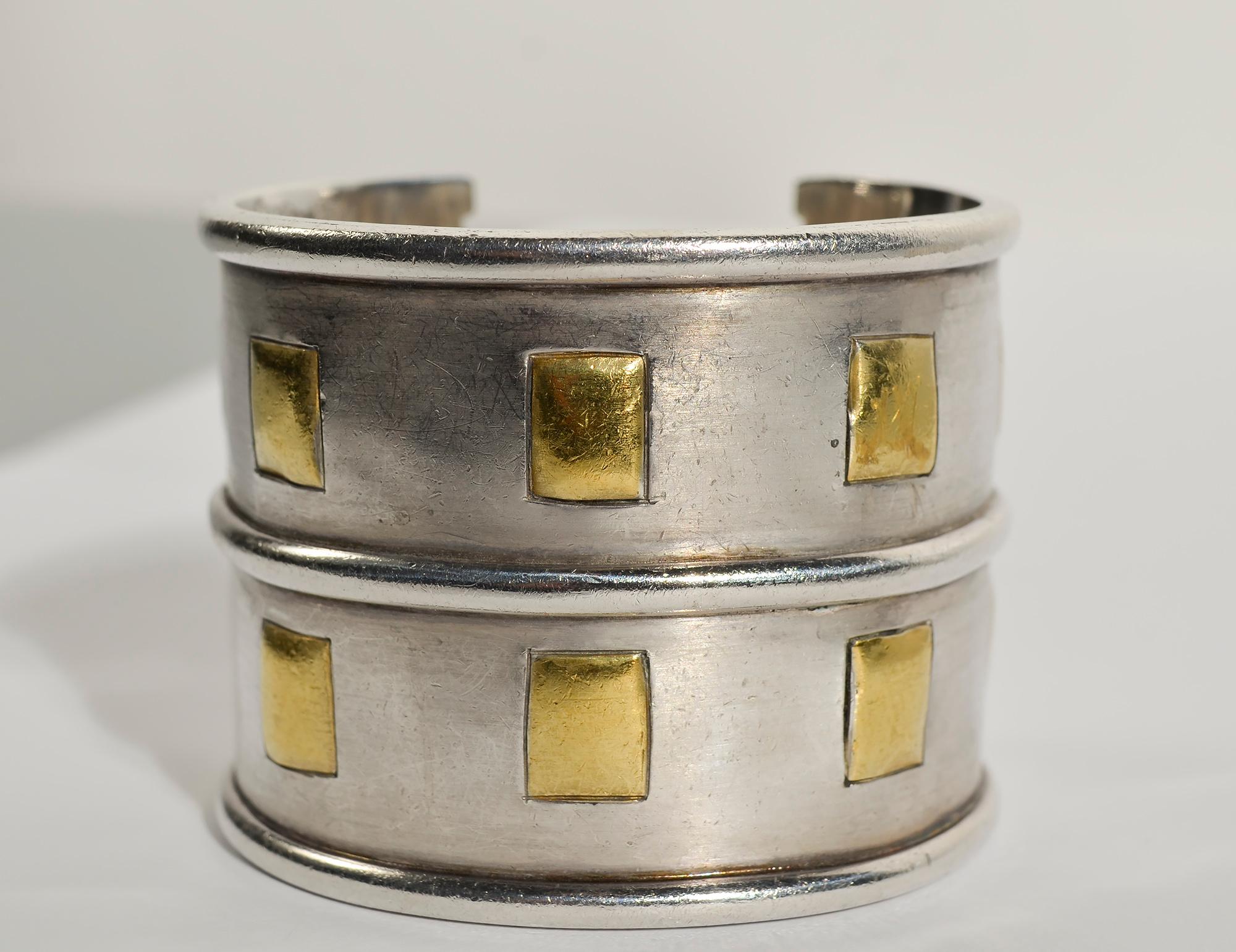 Wonderfully impactful cuff bracelet by Emilia Castillo. The body of the bracelet is sterling silver with a patchwork of squares of 24 karat gold. The bracelet is 2 inches wide. It measures 2 1/2 inches in diameter which can be adjusted to a slightly