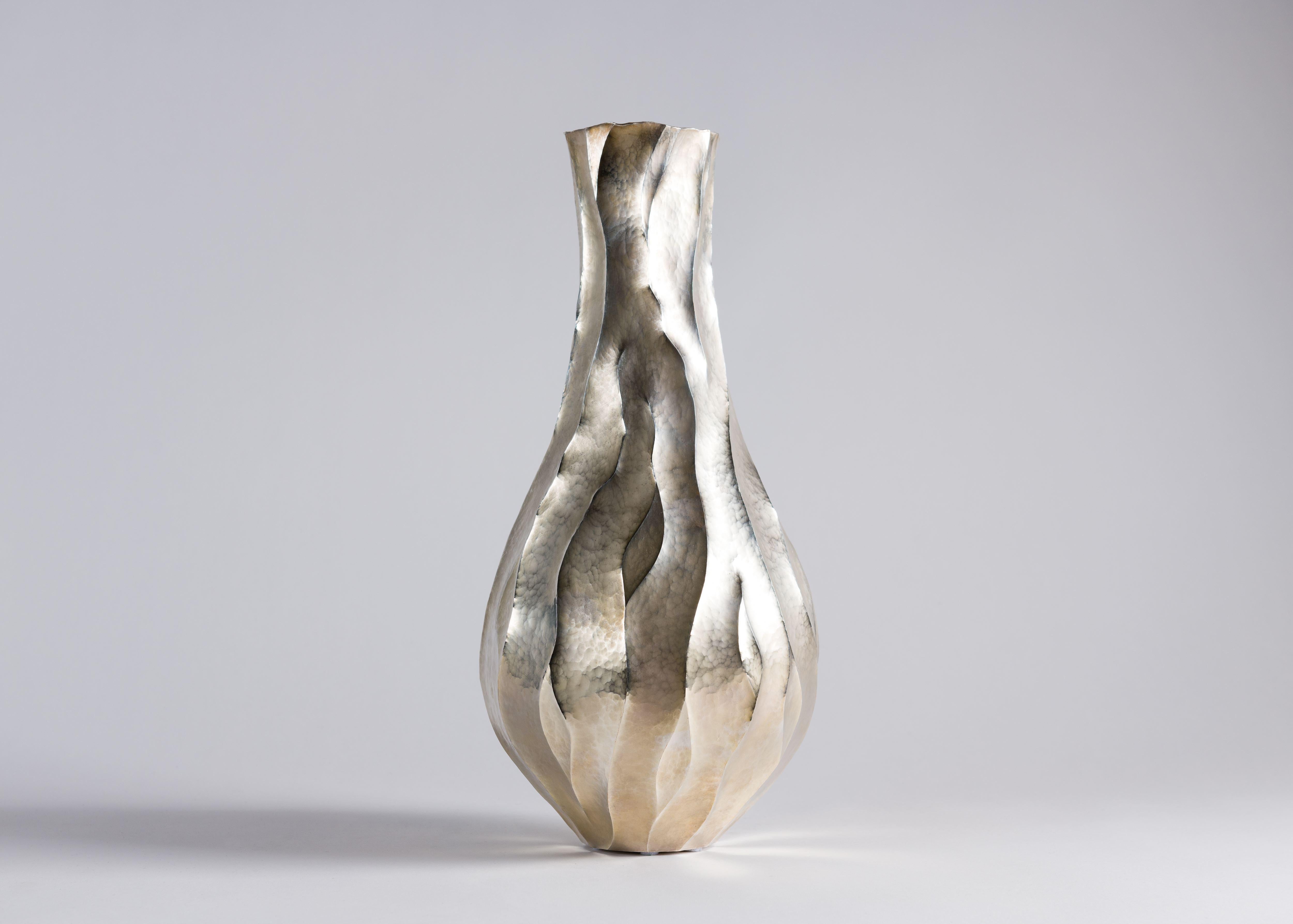 Formed from hand-hammered and silvered copper, this sleek vase gives the impression of roots straining through the earth toward the light, suggested by the subtle lines snaking up its surface.

Unique piece.
Stamped.