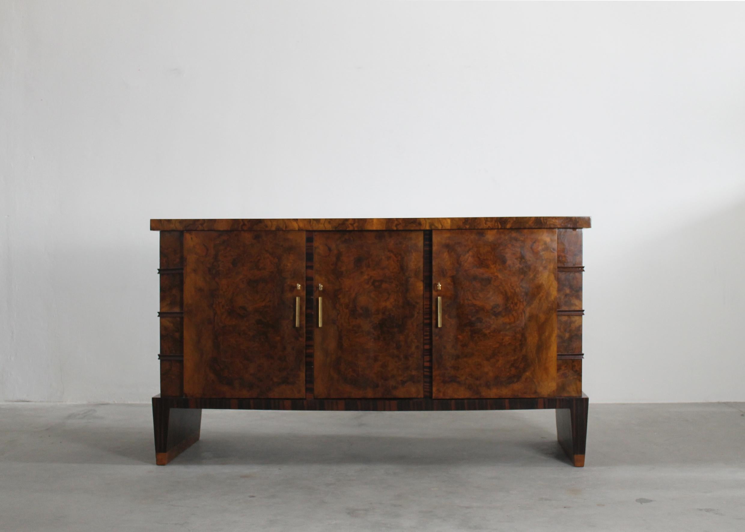 A mid-century sideboard with structure in walnut veneer with brass details, the sideboard presents three doors and six inner shelves. 
Designed by Emilio Lancia, Italian manufacture from the 1930s.

Emilio Lancia was an Italian architect, and one of