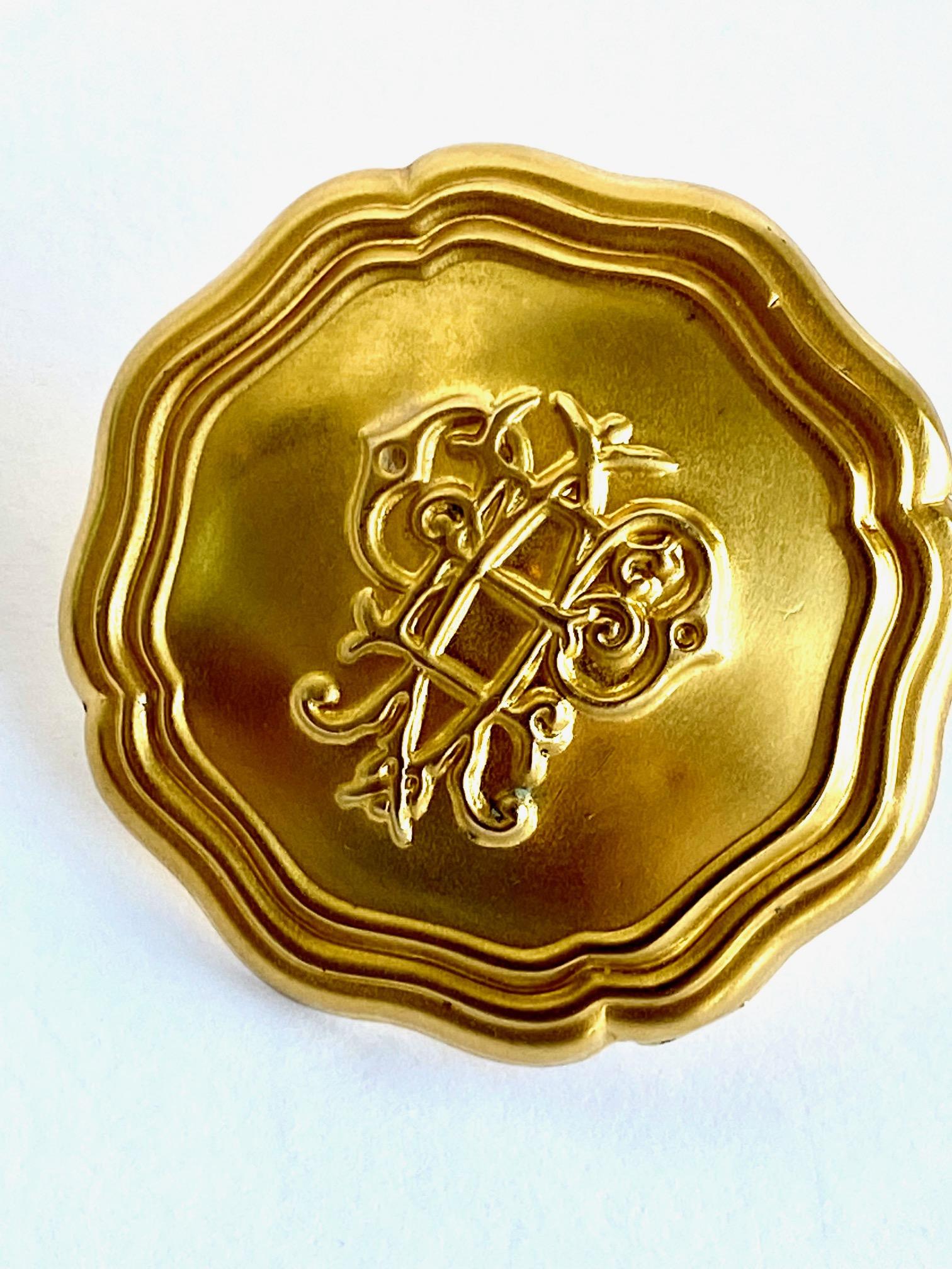 A large monogramed medallion top 1980s ring in satin and shiny gold by iconic fashion house Emilio Pucci. The large top medallion is satin gold, measures 1.75 inches in diameter and set onto a shiny gold tone open band. The medallion has a light