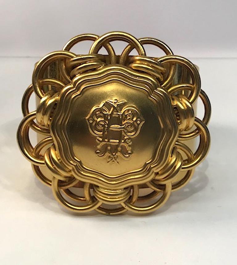 A large cuff style 1980s satin and shiny gold tone bracelet by iconic fashion house Emilio Pucci. The large top medallion is satin gold and measures 3 inches wide and 2.75 high. The center is slightly domed and measures .75 inched high. In the