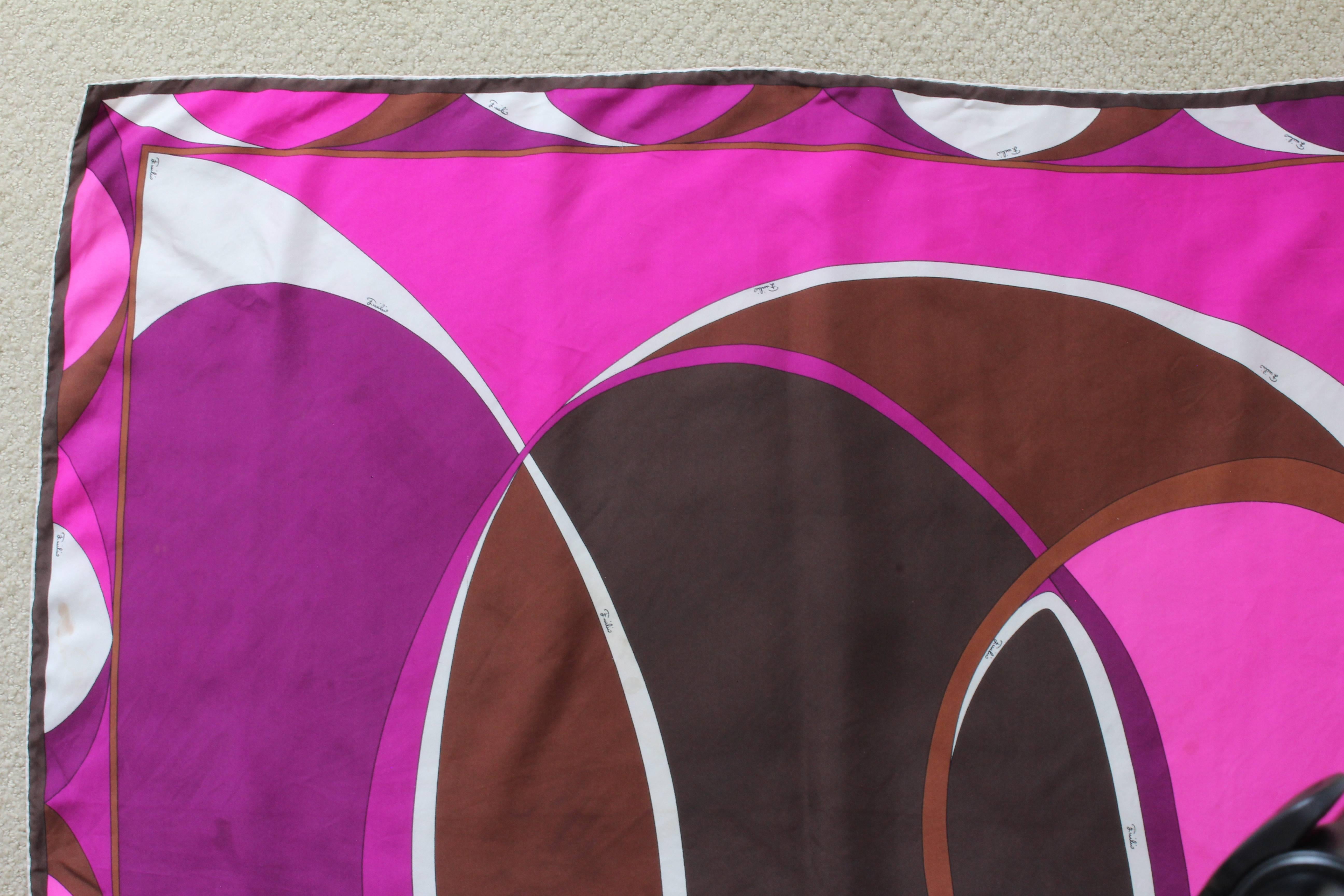 This colorful scarf was made by Emilio Pucci, most likely in the 1980s. Made from silk twill, it features an abstract pattern in shades of brown, purple, pink and white, and hand rolled hems.  

The bold colors and abstract design are perfect for