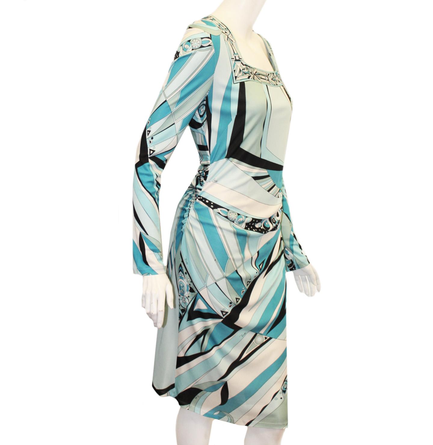Emilio Pucci blue and turquoise color hues, geometric print dress is gathered at the waist and includes a square neckline.  Dress has long sleeves and is lined in white viscose.  Dress has some minor pulls and stains.  Back zipper for closure.  Made