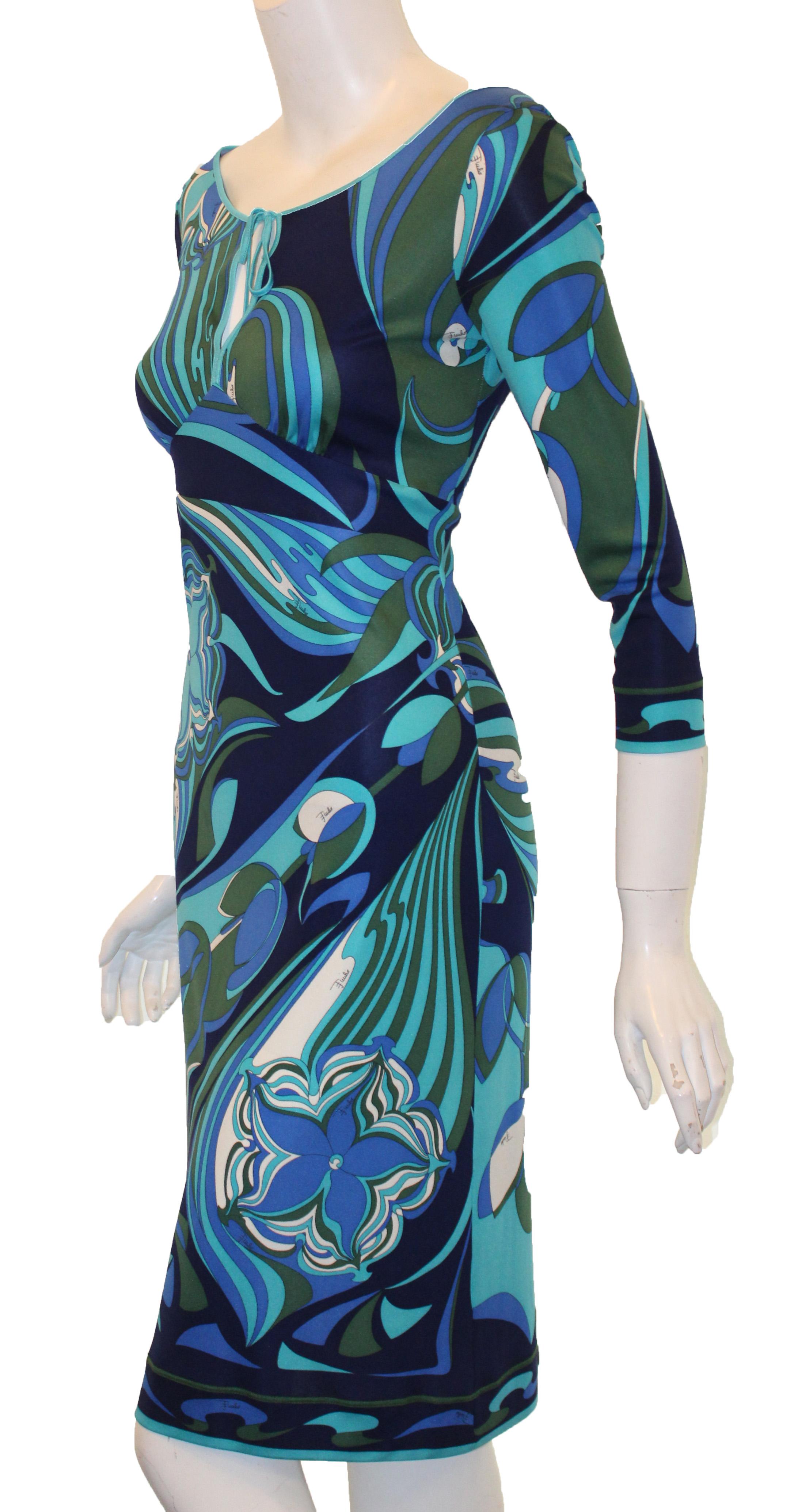 Emilio Pucci multi blue tones, boat collar dress includes a peek a boo opening at front.  This empire waist with 3/4 sleeves dress on an indefinable floral print is not lined.  The hem this garment contains a band trim of same fabric colors for