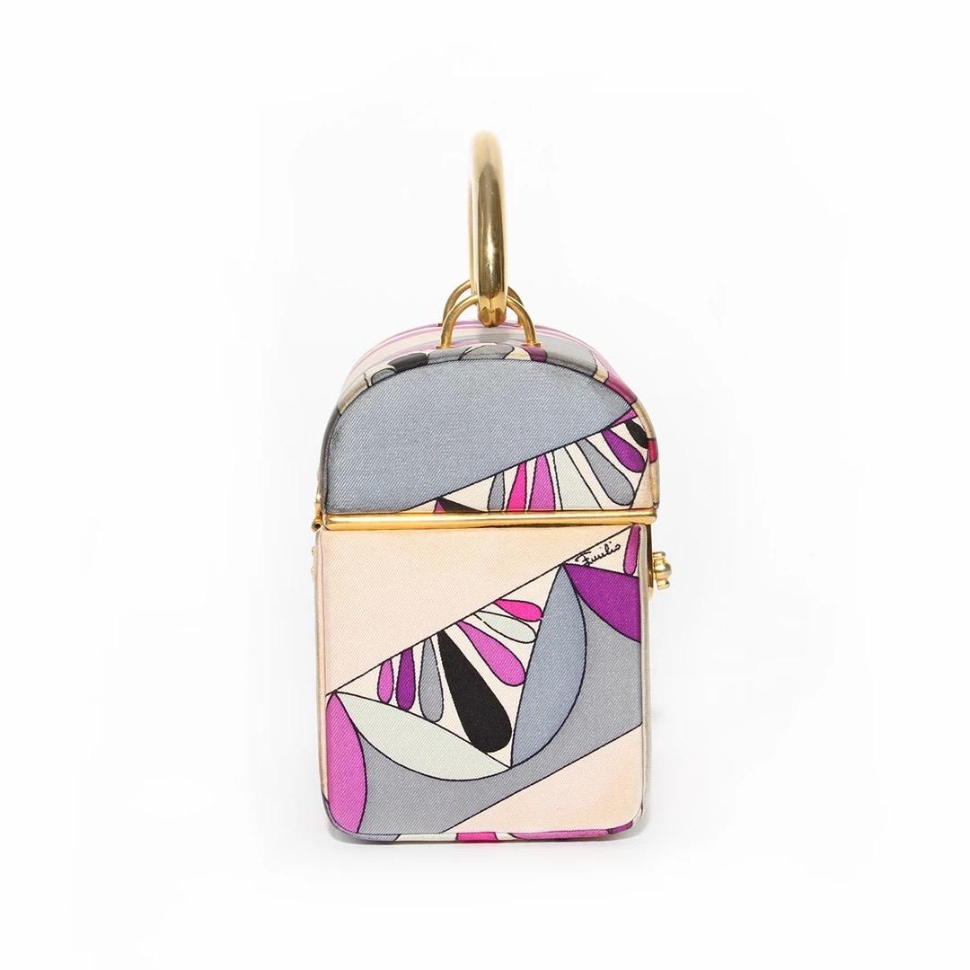 Emilio Pucci Handbag 
Vintage 
Circa 1960's 
Made in Italy 
Purple, pink, grey and white classic Pucci print 
Silk exterior 
Gold-tone top handle handle 
Gold hardware 
Turn lock closure 
Rounded top 
White leather interior 
Single open pocket 
Fair