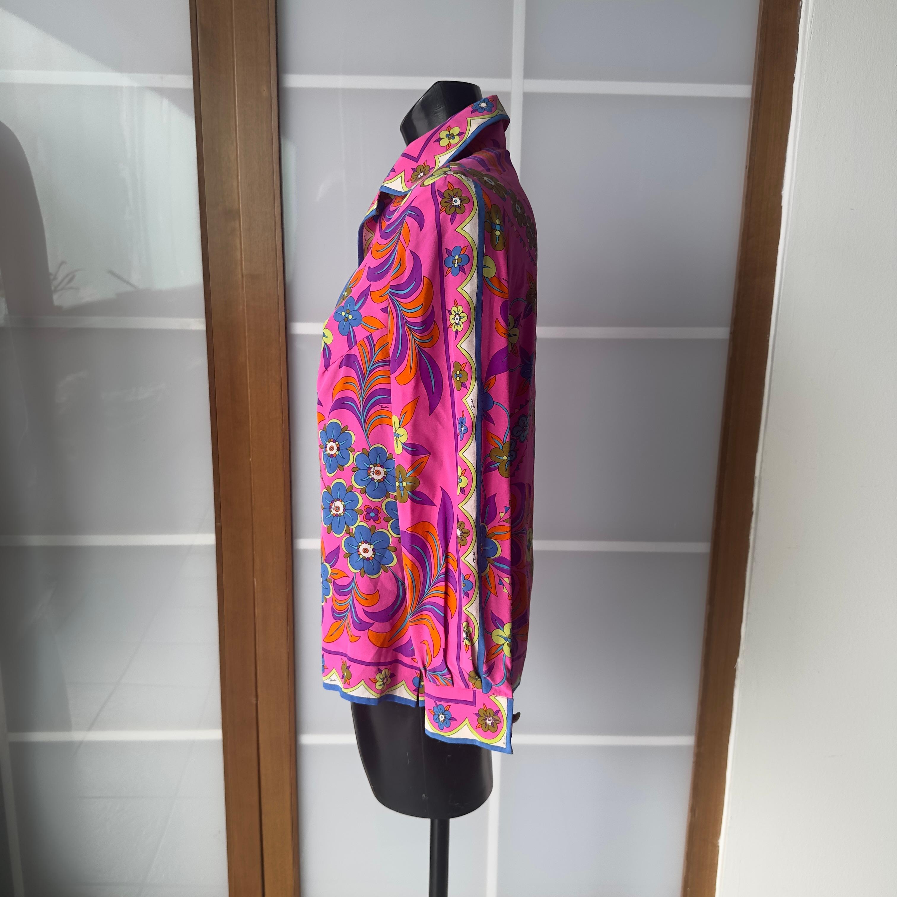 Iconic vintage Emilio Pucci shirt from the 1970s, made of 100% pure silk with the unmistakable multicolored floral print on a fuchsia base. The psychedelic design, signed in the fabric with the famous 