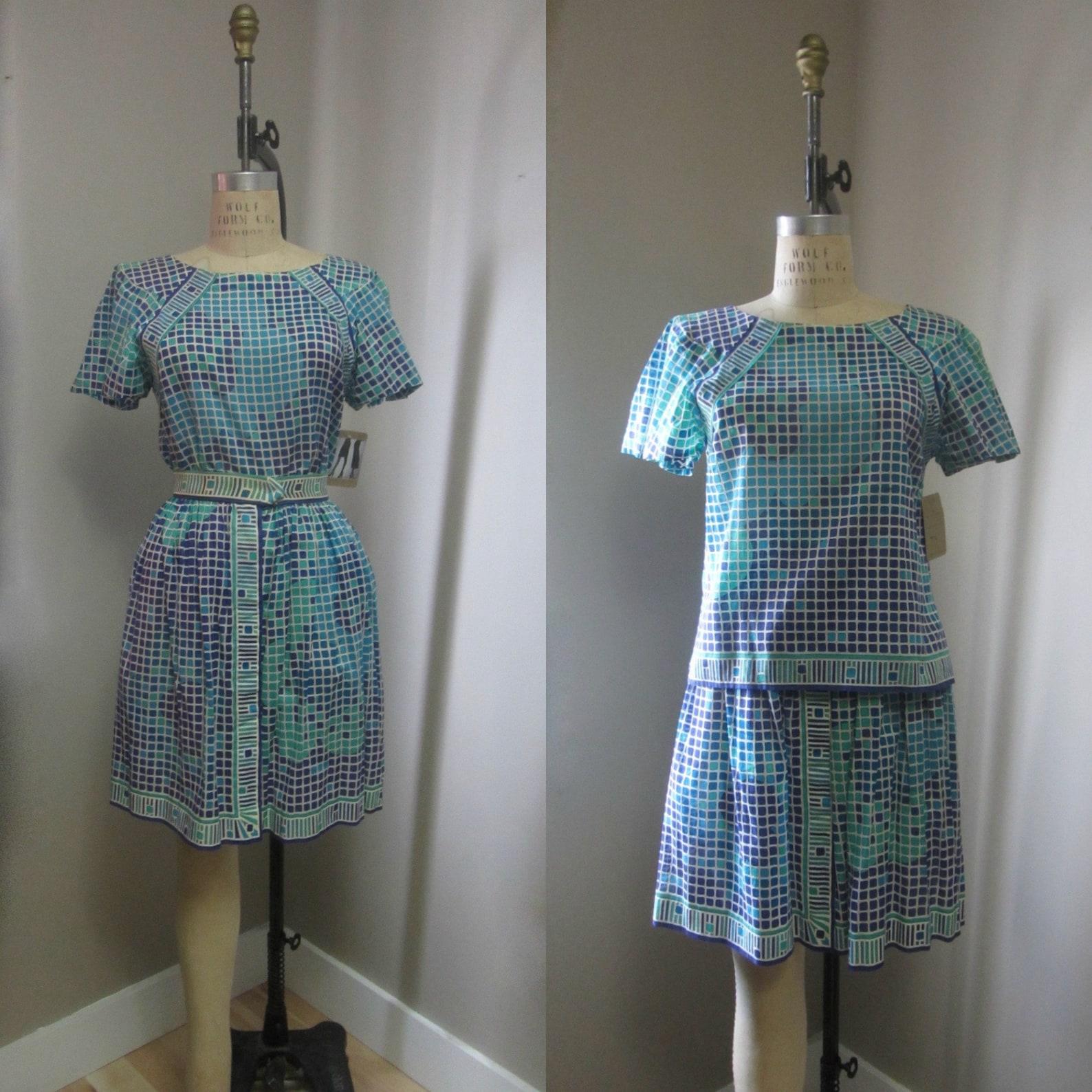 Vintage Emilio Pucci two piece blouse and skirt set. 
Geometric print in shades of blue, green, purple, and cream. 
Short flutter sleeve blouse with cropped body, side split hem & round collar. 
Full mini skirt with fitted waist, center kick pleats